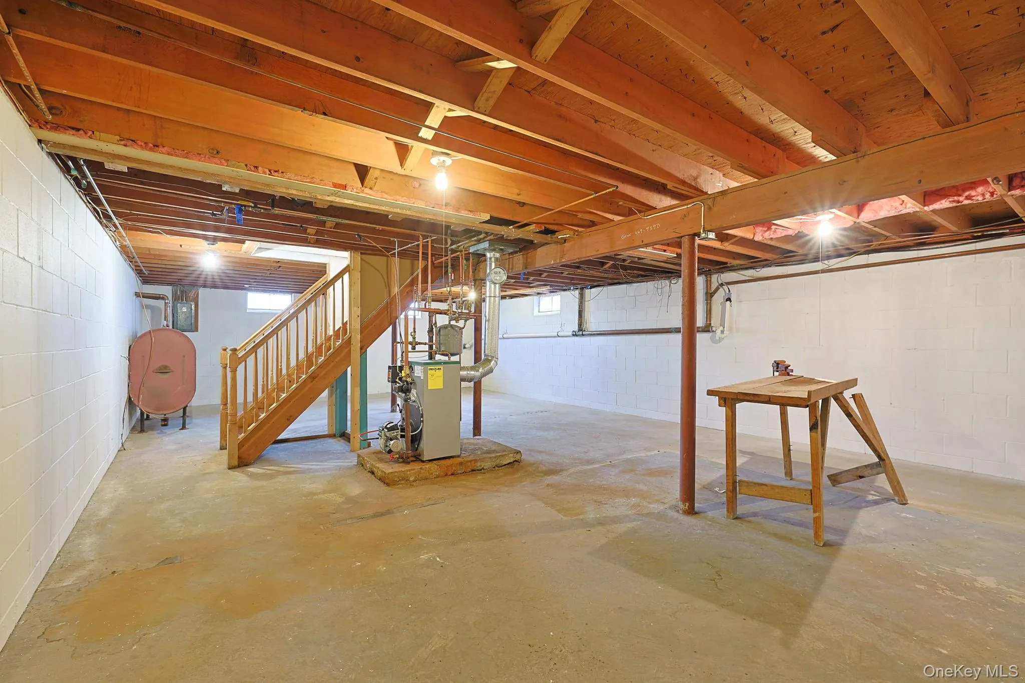 Basement featuring exposed wooden beams, concrete flooring, and painted cinder block walls Basement featuring exposed wooden beams, concrete flooring, and painted cinder block walls