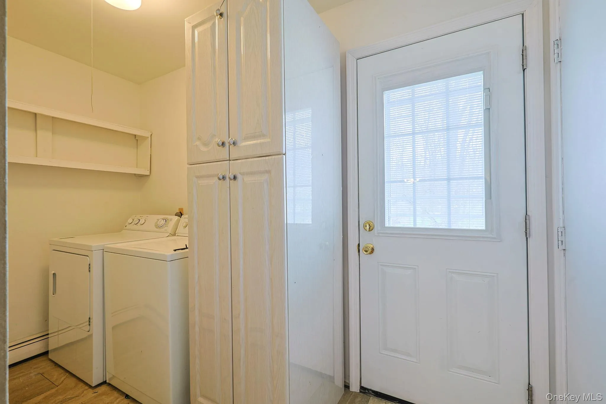 Utility area featuring a white door with a window, white cabinetry, and an open shelf Utility area featuring a white door with a window, white cabinetry, and an open shelf