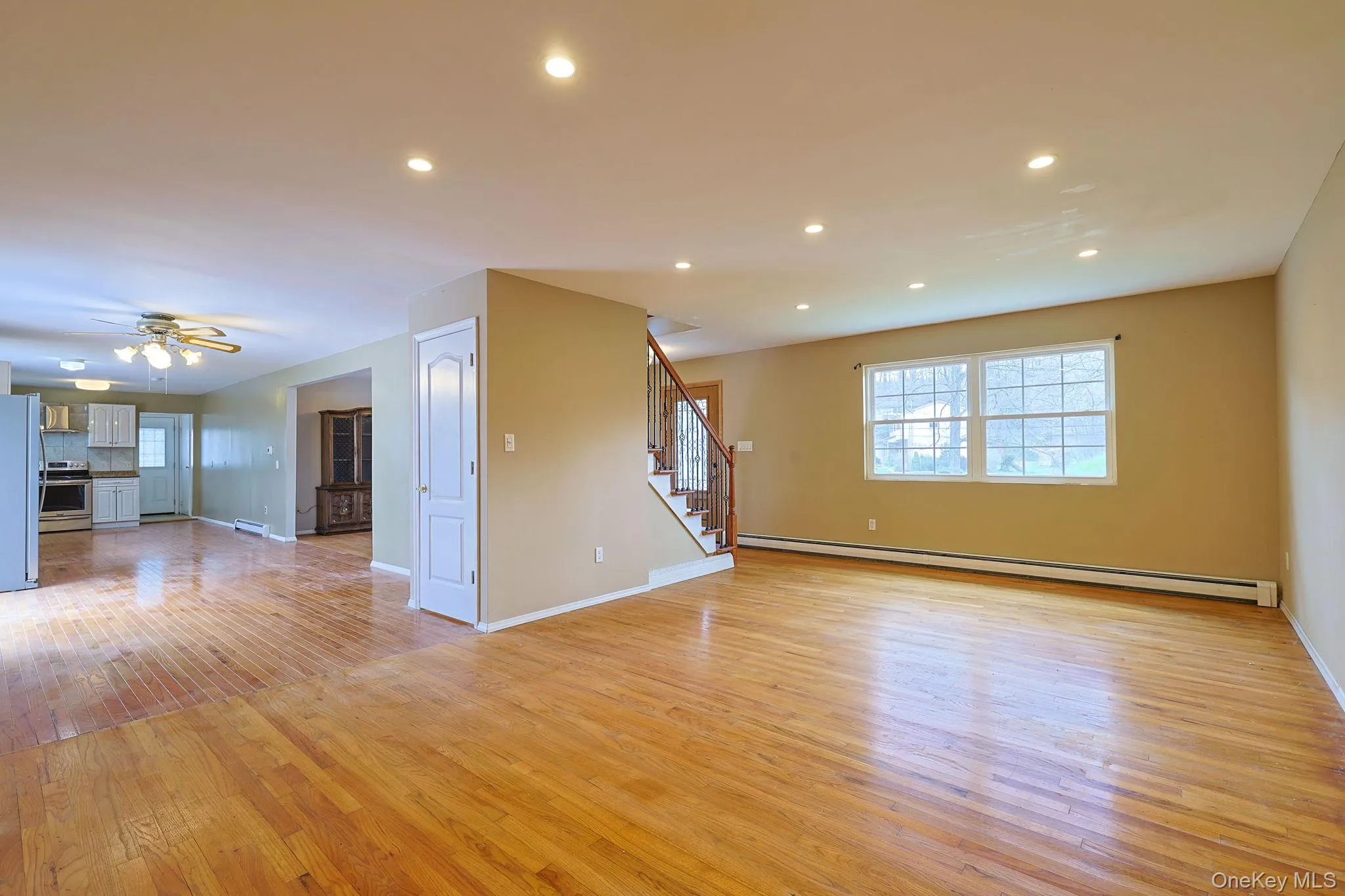 This spacious living area features hardwood floors, recessed lighting, and ample natural light from a window This spacious living area features hardwood floors, recessed lighting, and ample natural light from a window
