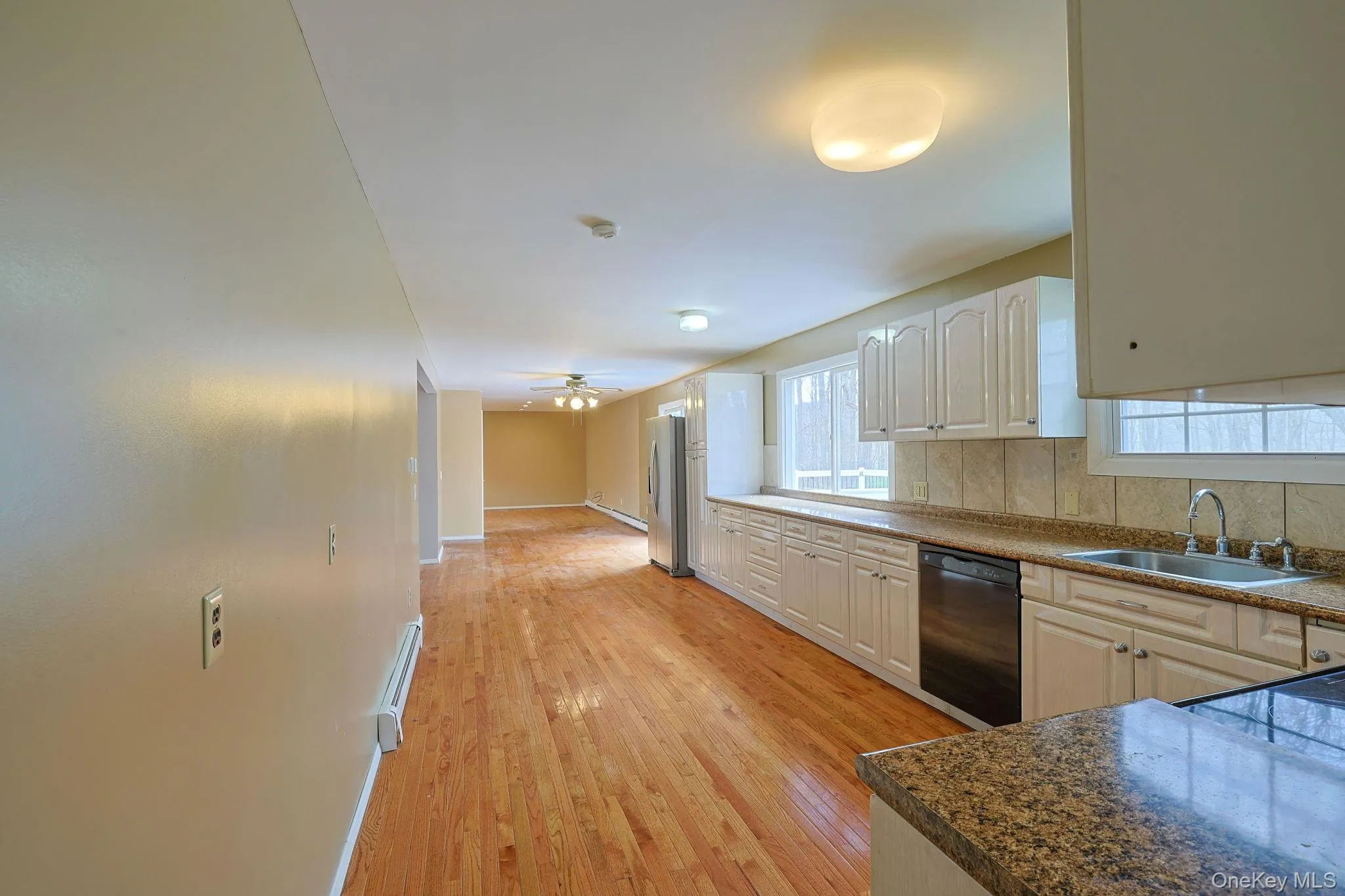 Kitchen featuring hardwood floors, white cabinetry, granite countertops, and stainless steel appliances Kitchen featuring hardwood floors, white cabinetry, granite countertops, and stainless steel appliances