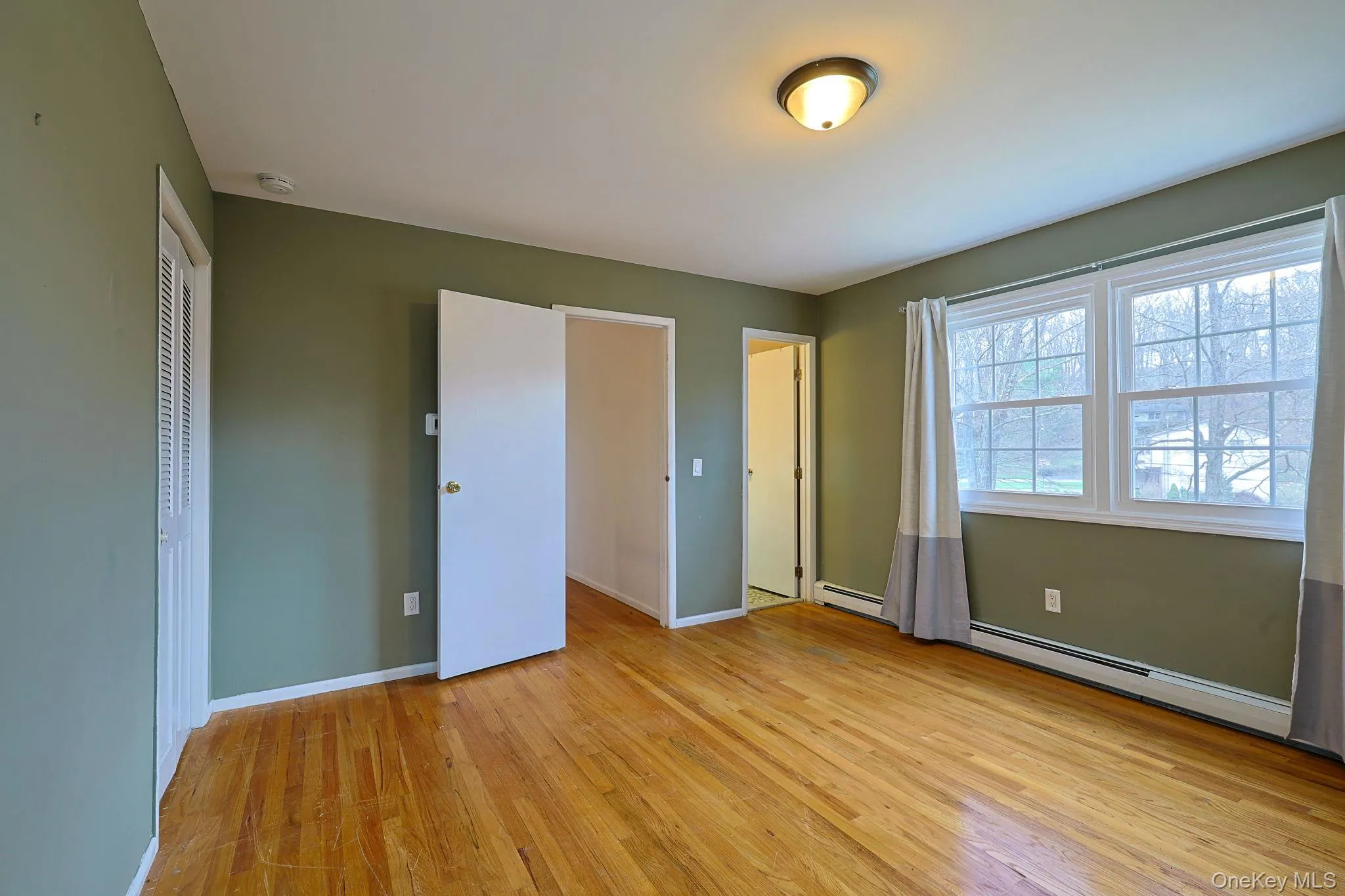 This room features hardwood floors, a neutral wall color, and windows providing natural light This room features hardwood floors, a neutral wall color, and windows providing natural light