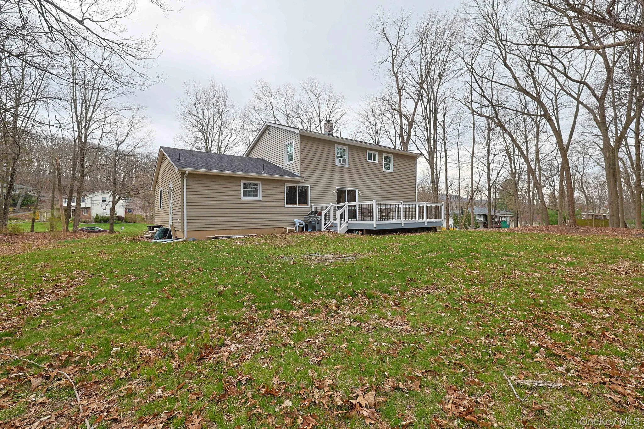 The property features a spacious yard with a green lawn, surrounded by numerous mature trees The property features a spacious yard with a green lawn, surrounded by numerous mature trees