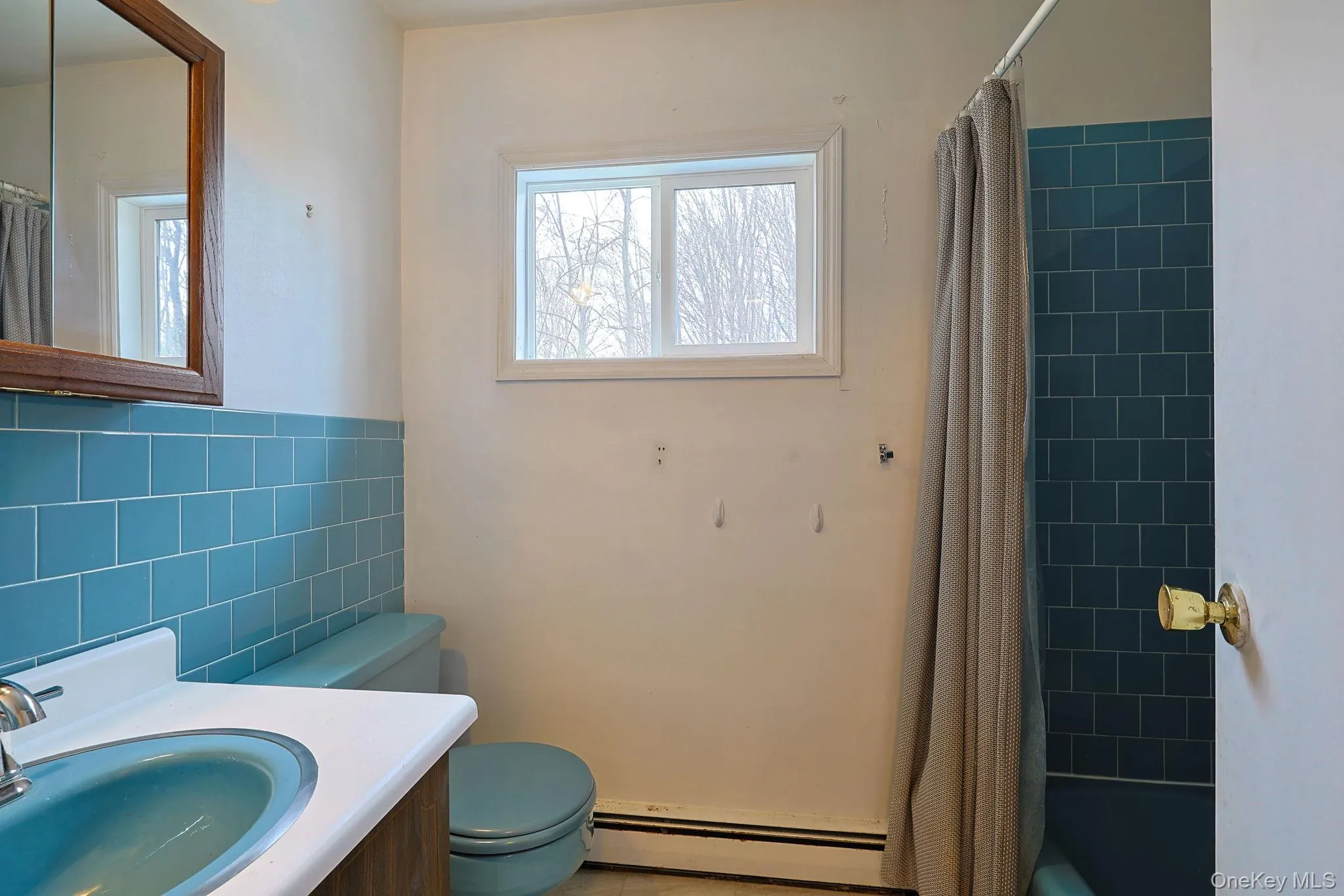 The bathroom features a window, a vanity with a basin, and a toilet The bathroom features a window, a vanity with a basin, and a toilet