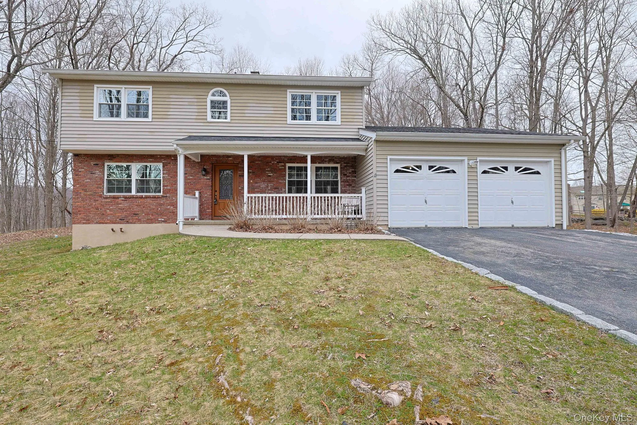 The property features a brick and siding exterior, a two-car garage with decorative windows, and a covered front porch The property features a brick and siding exterior, a two-car garage with decorative windows, and a covered front porch