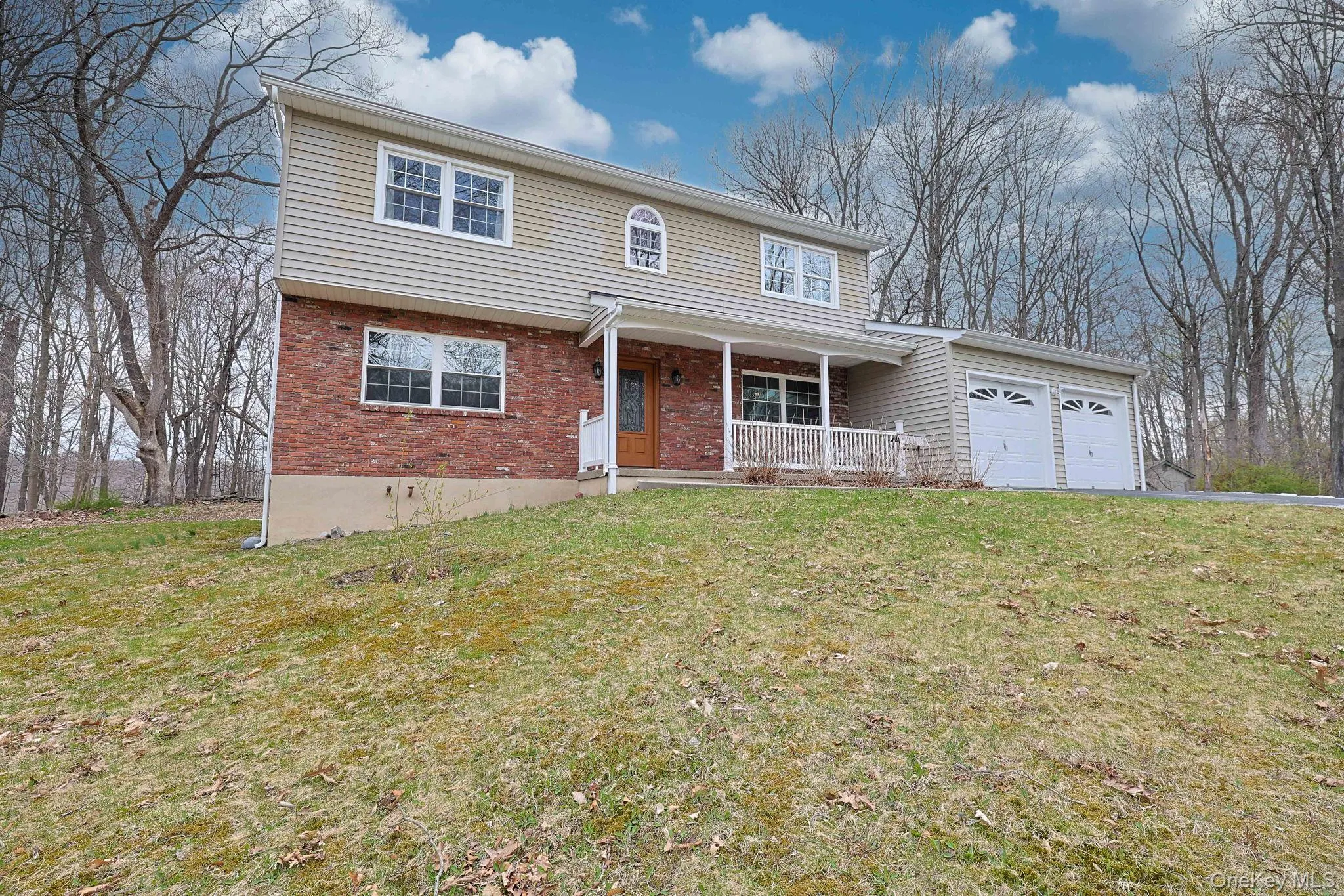 The property features a two-story exterior with a brick and siding facade, a covered front porch, and a two-car garage The property features a two-story exterior with a brick and siding facade, a covered front porch, and a two-car garage