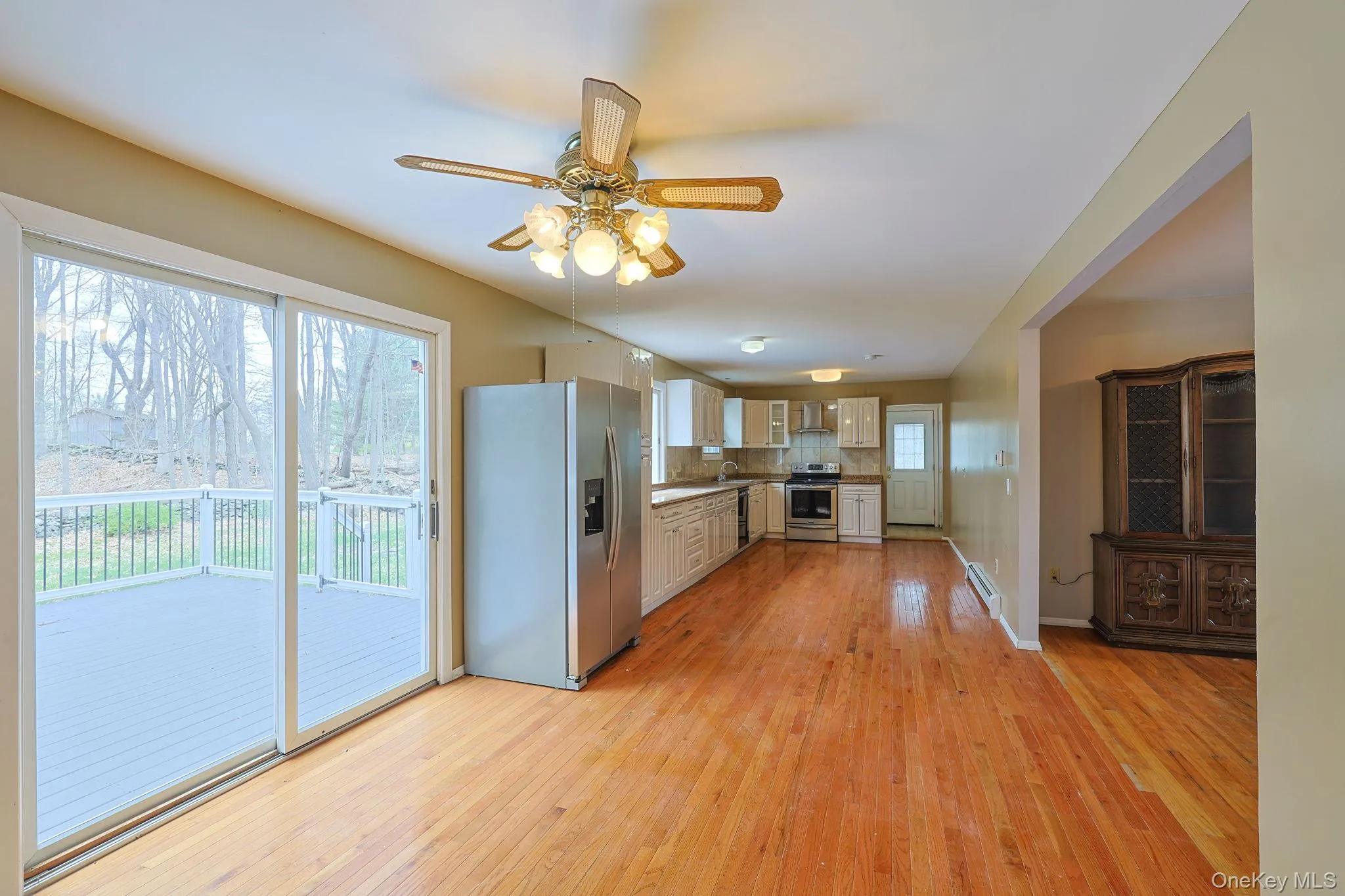 Open concept living area featuring hardwood flooring, a ceiling fan, and sliding glass doors that open to a deck Open concept living area featuring hardwood flooring, a ceiling fan, and sliding glass doors that open to a deck