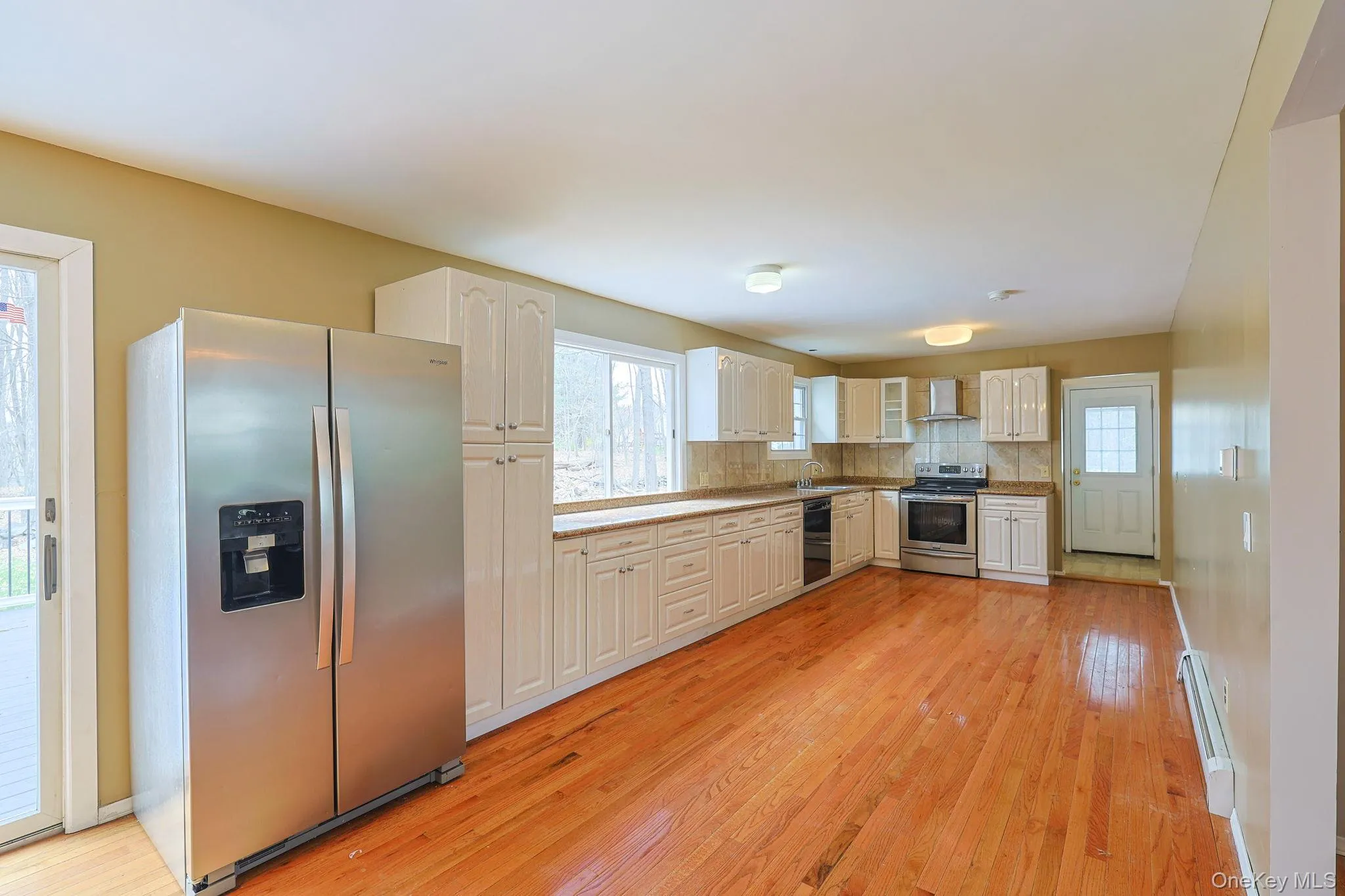 The kitchen features stainless steel appliances, extensive white cabinetry, and hardwood floors The kitchen features stainless steel appliances, extensive white cabinetry, and hardwood floors