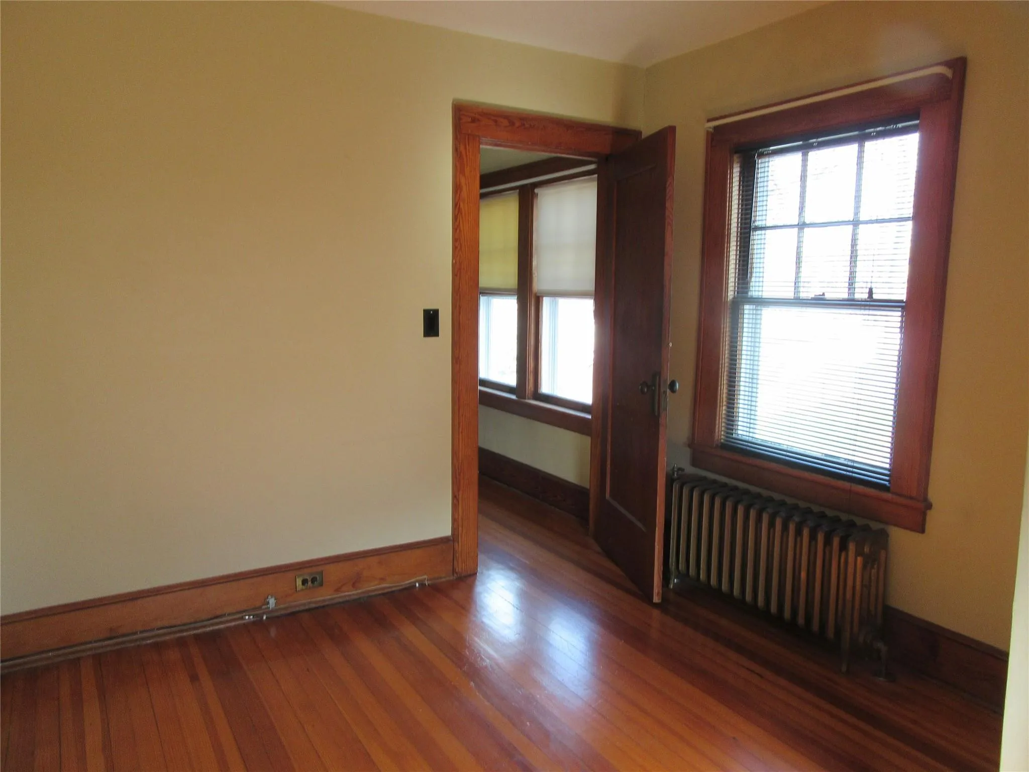 Spare room with radiator heating unit, baseboards, and wood finished floors Spare room with radiator heating unit, baseboards, and wood finished floors