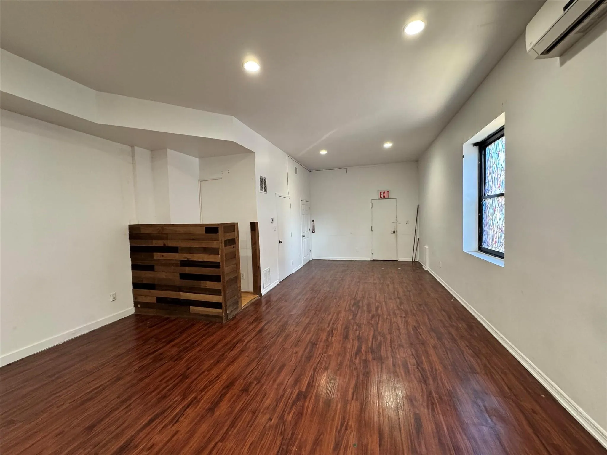 Below grade area featuring recessed lighting, wood finished floors, and a wall mounted air conditioner Below grade area featuring recessed lighting, wood finished floors, and a wall mounted air conditioner