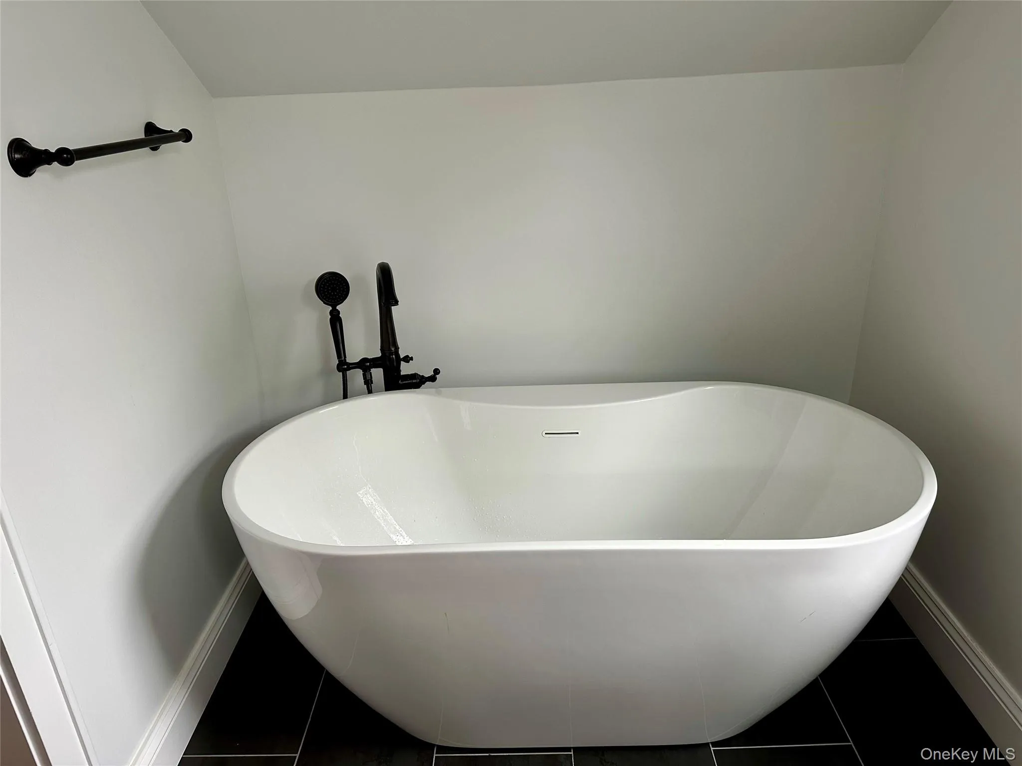 Bathroom with tile patterned floors, baseboards, and a freestanding bath Bathroom with tile patterned floors, baseboards, and a freestanding bath