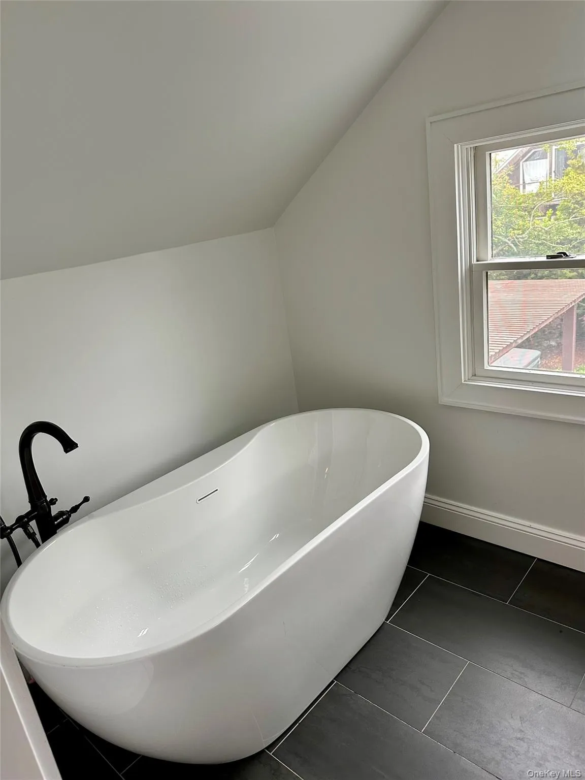Bathroom featuring lofted ceiling, a soaking tub, and baseboards Bathroom featuring lofted ceiling, a soaking tub, and baseboards