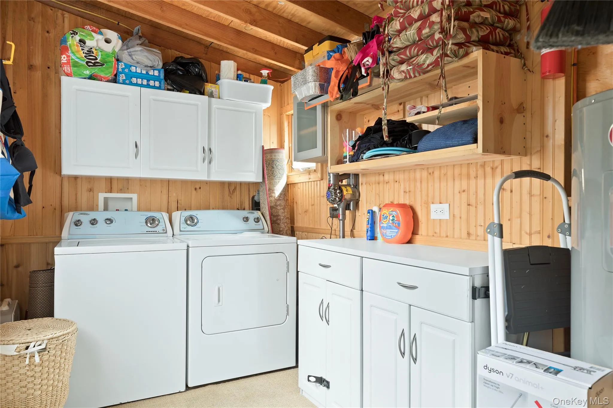 Laundry area featuring wood walls, cabinet space, and washer and clothes dryer Laundry area featuring wood walls, cabinet space, and washer and clothes dryer