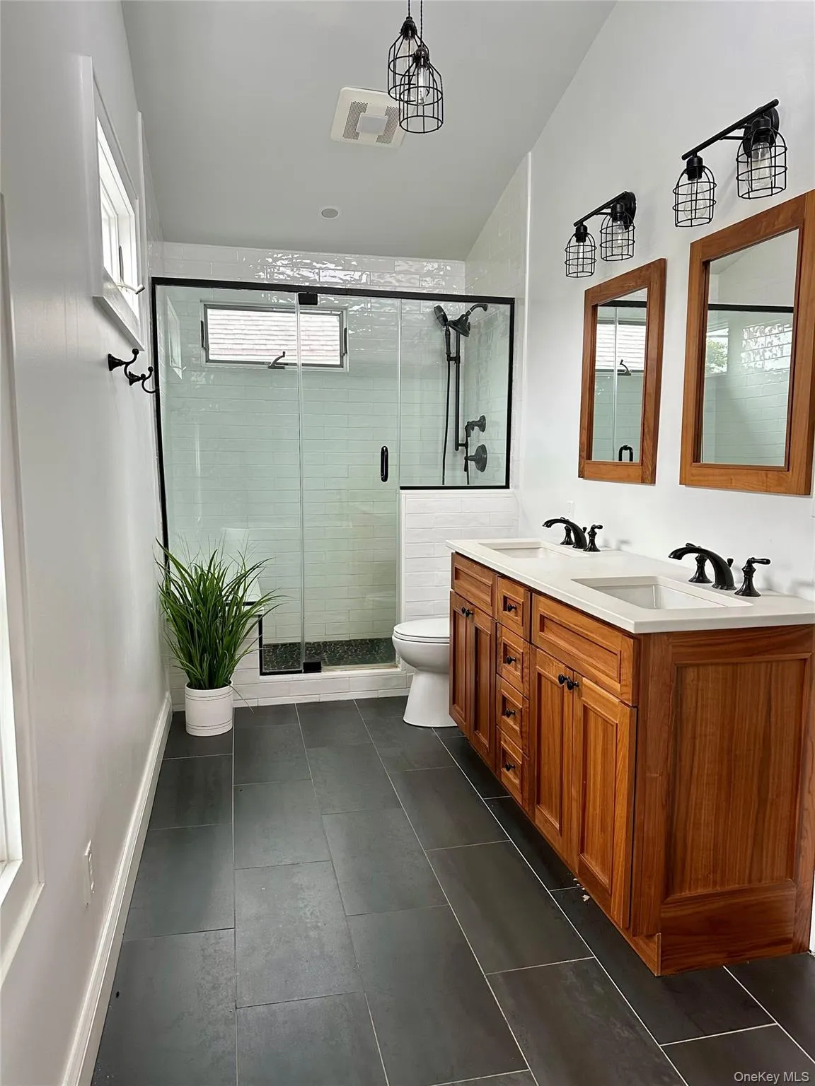 Bathroom featuring toilet, double vanity, a sink, and a shower stall Bathroom featuring toilet, double vanity, a sink, and a shower stall