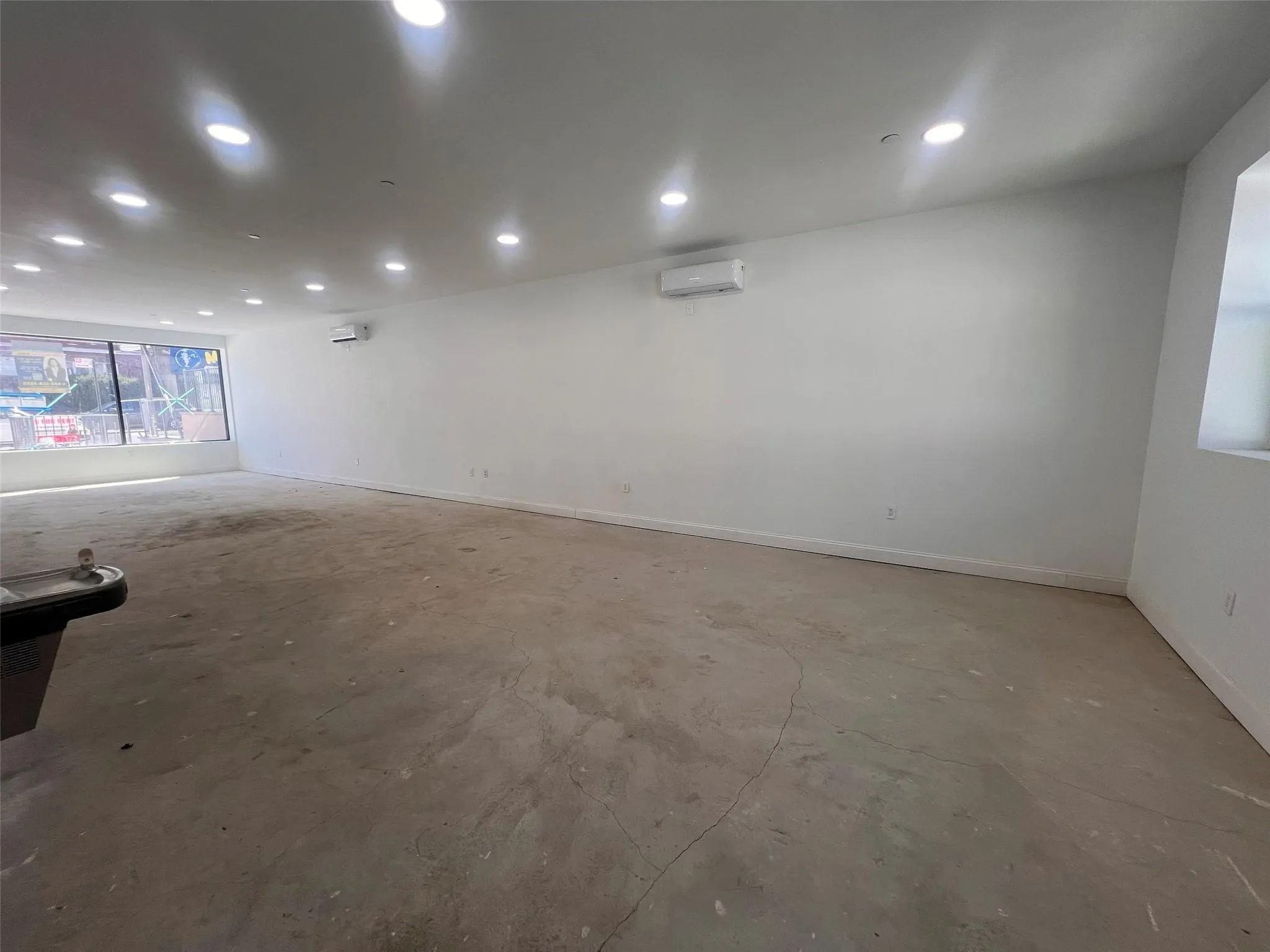 Spare room with an AC wall unit, concrete flooring, baseboards, and recessed lighting Spare room with an AC wall unit, concrete flooring, baseboards, and recessed lighting