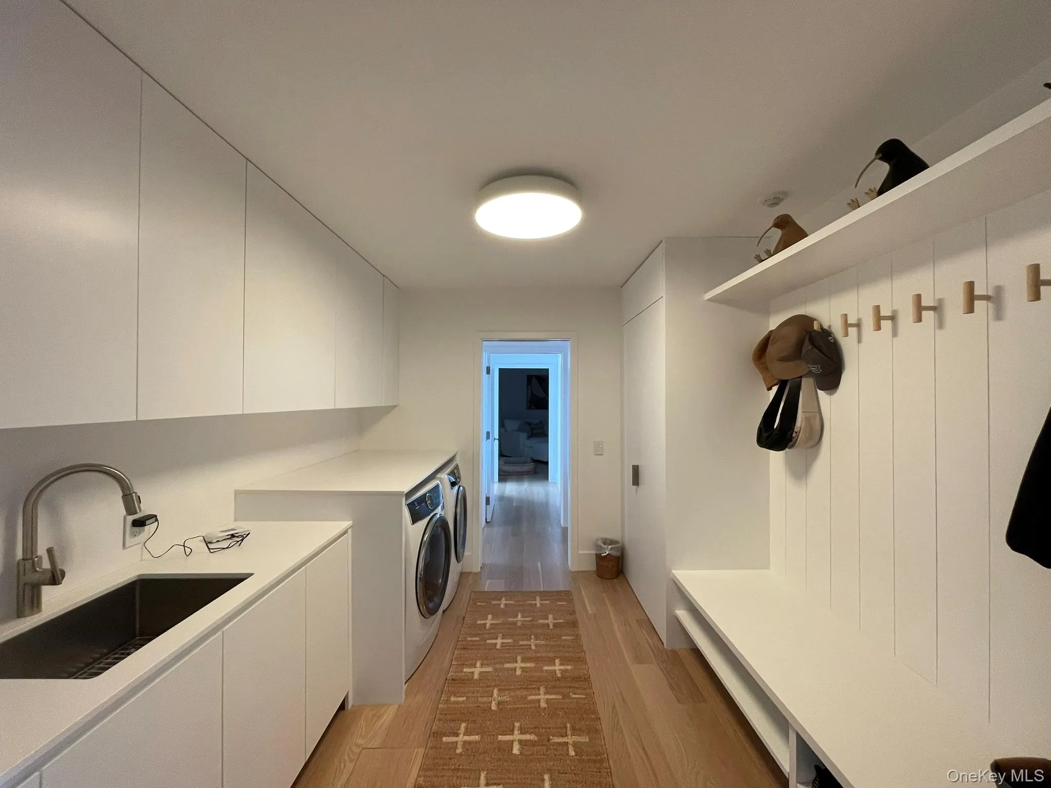 Washroom with a sink, light wood-style flooring, cabinet space, and washing machine and dryer Washroom with a sink, light wood-style flooring, cabinet space, and washing machine and dryer