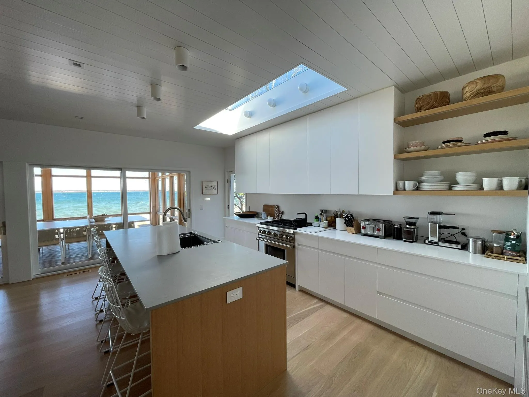 Kitchen with high end stainless steel range, a kitchen breakfast bar, a skylight, a kitchen island with sink, and a sink Kitchen with high end stainless steel range, a kitchen breakfast bar, a skylight, a kitchen island with sink, and a sink