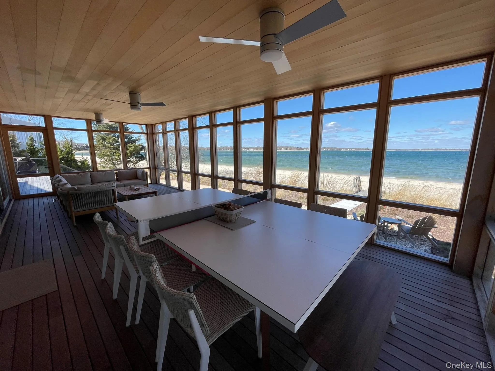 Sunroom with a beach view, ceiling fan, and outdoor dining area Sunroom with a beach view, ceiling fan, and outdoor dining area