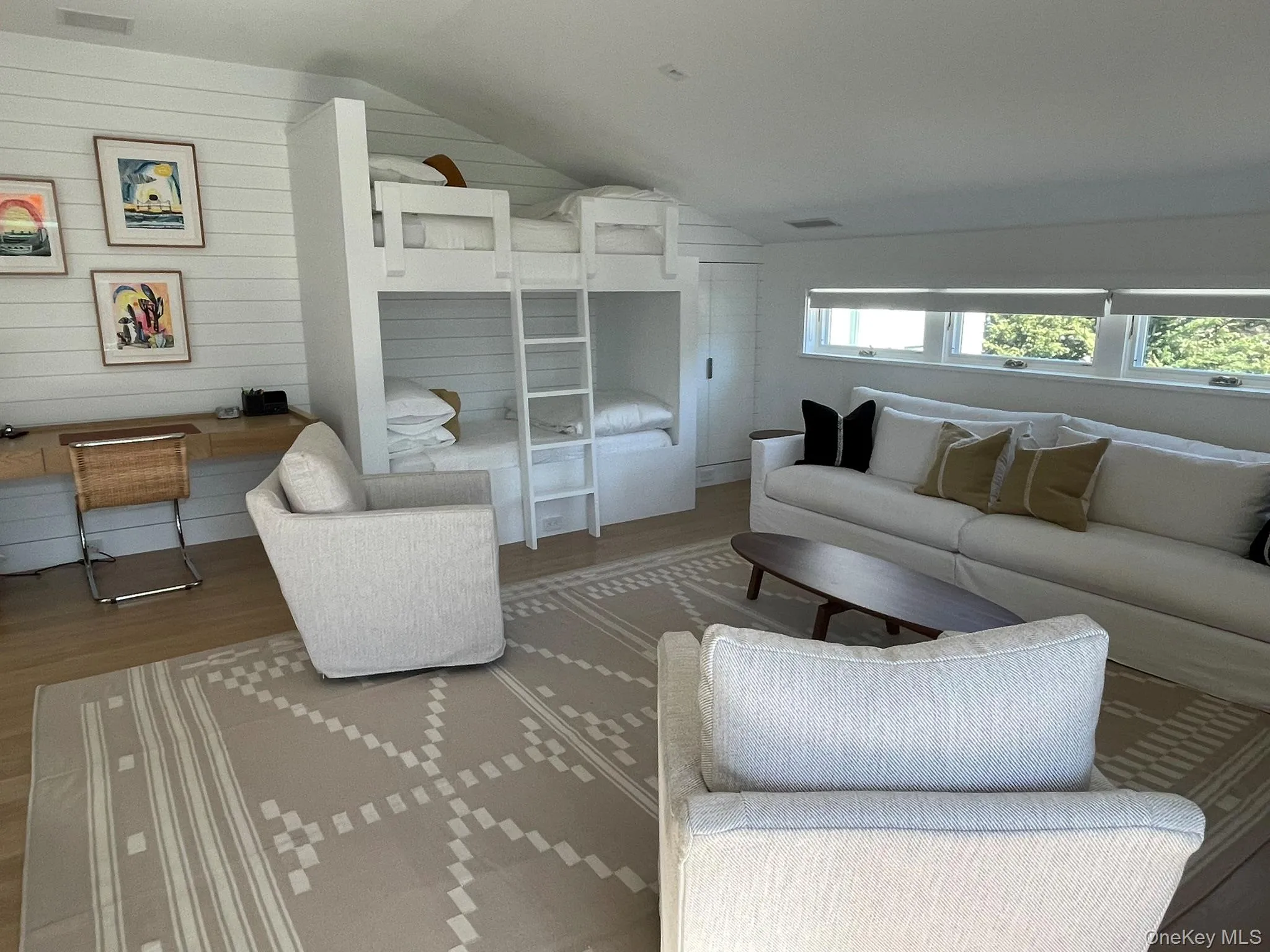 Living area featuring a healthy amount of sunlight, lofted ceiling, wooden walls, and wood finished floors Living area featuring a healthy amount of sunlight, lofted ceiling, wooden walls, and wood finished floors