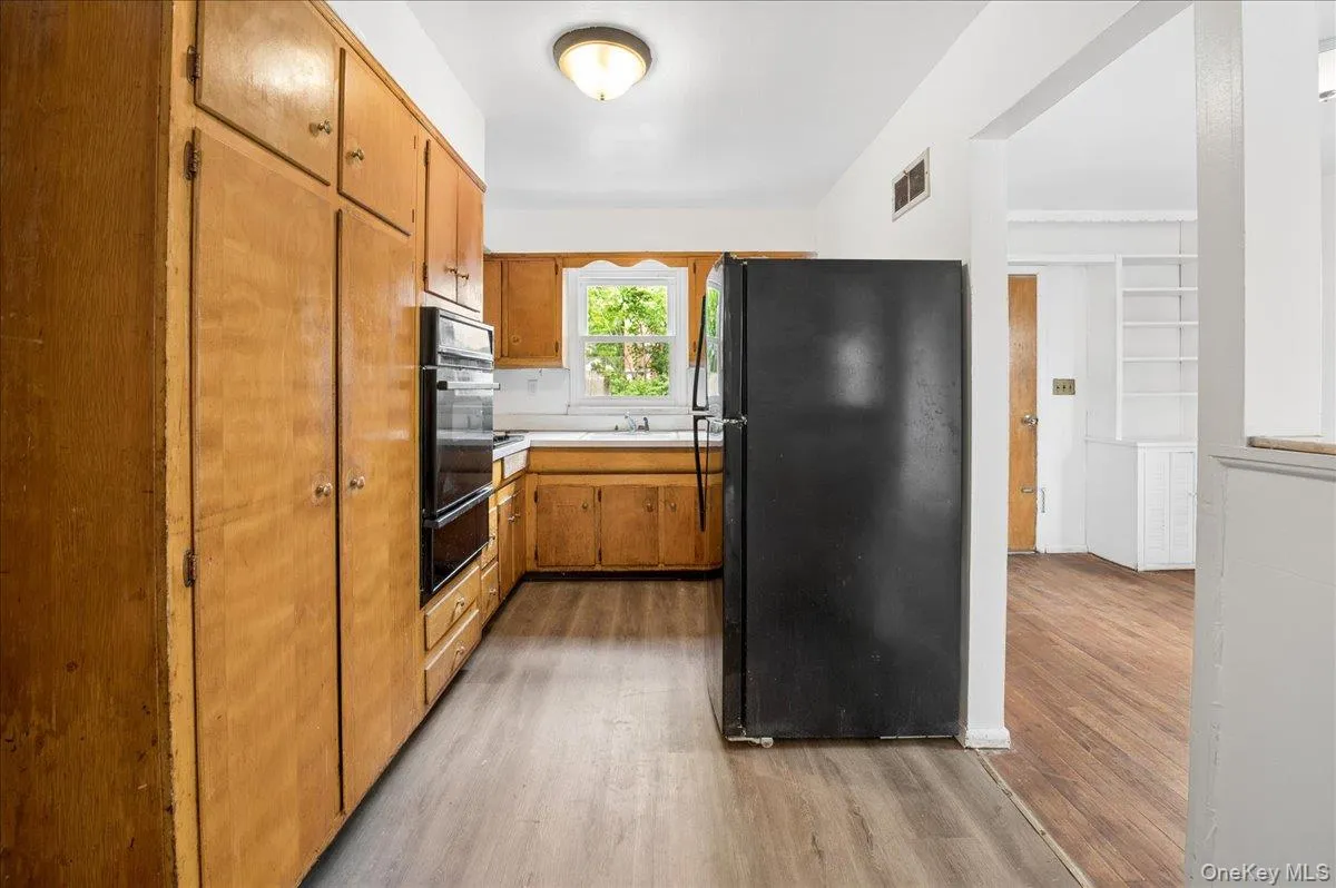 Kitchen featuring extensive wood cabinetry, built-in double ovens, and wood-finish flooring Kitchen featuring extensive wood cabinetry, built-in double ovens, and wood-finish flooring