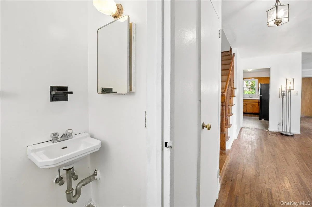 Compact powder room featuring a wall-mounted sink with chrome fixtures and a mirrored medicine cabinet Compact powder room featuring a wall-mounted sink with chrome fixtures and a mirrored medicine cabinet