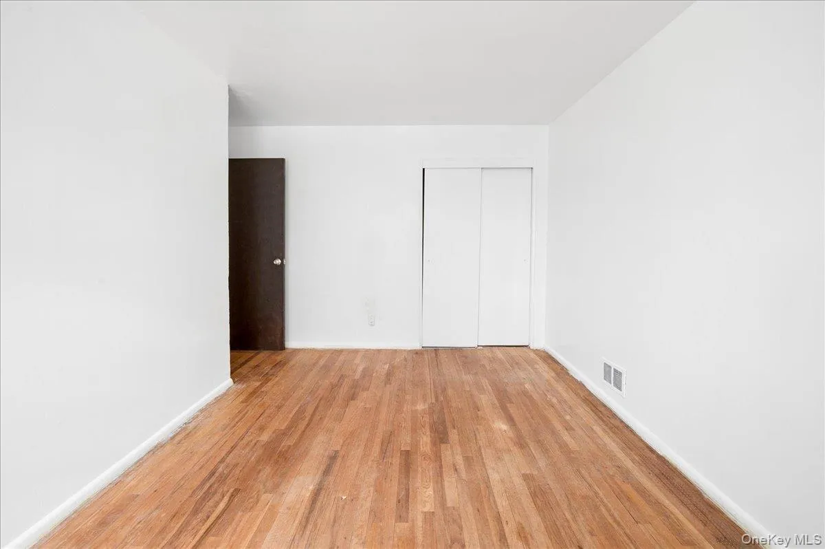 Hardwood flooring extends throughout this room, featuring white walls and baseboards Hardwood flooring extends throughout this room, featuring white walls and baseboards