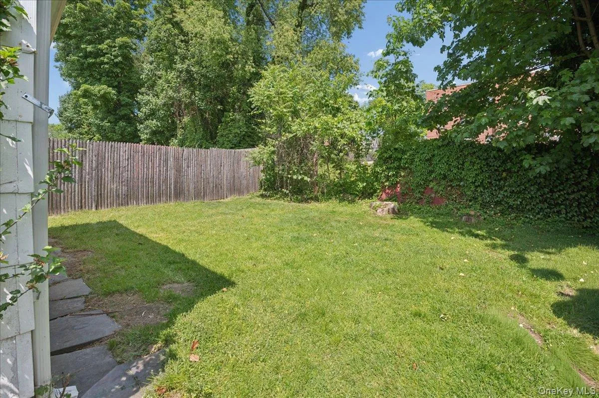 Expansive lawn area bordered by a wood fence and mature greenery Expansive lawn area bordered by a wood fence and mature greenery