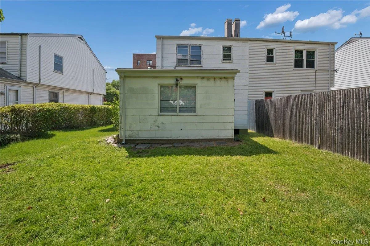 Expansive rear yard featuring a manicured lawn, an established privacy hedge, and a wood privacy fence Expansive rear yard featuring a manicured lawn, an established privacy hedge, and a wood privacy fence