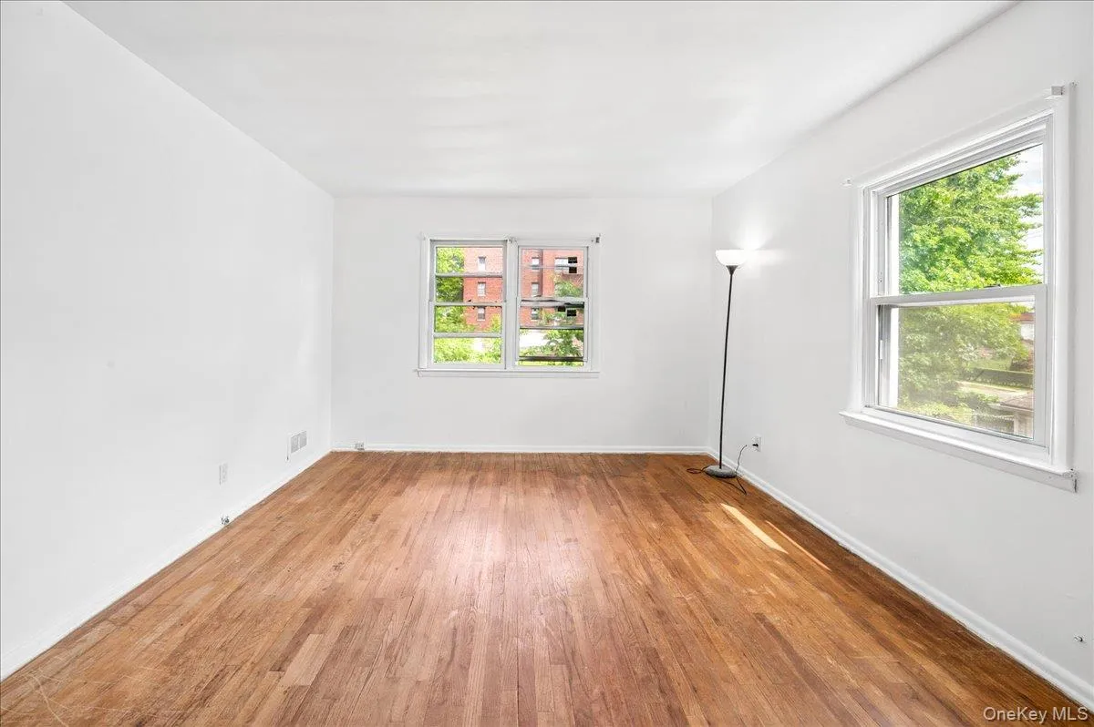 Hardwood flooring throughout a spacious room with white walls Hardwood flooring throughout a spacious room with white walls