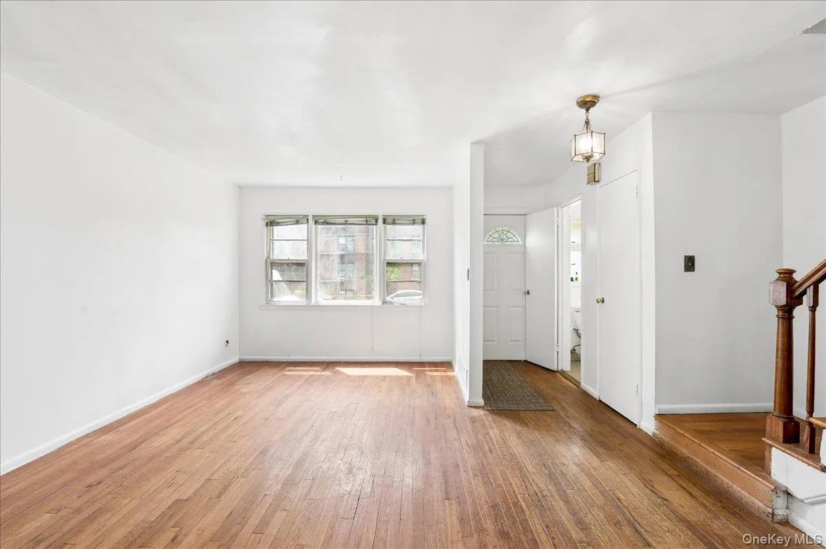 Living space featuring wood-finish flooring, a triple window arrangement, and white painted walls Living space featuring wood-finish flooring, a triple window arrangement, and white painted walls
