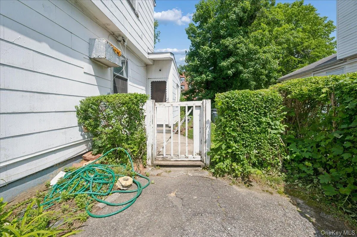 Gated entry alongside a structure with horizontal siding and a large mature tree in the background Gated entry alongside a structure with horizontal siding and a large mature tree in the background