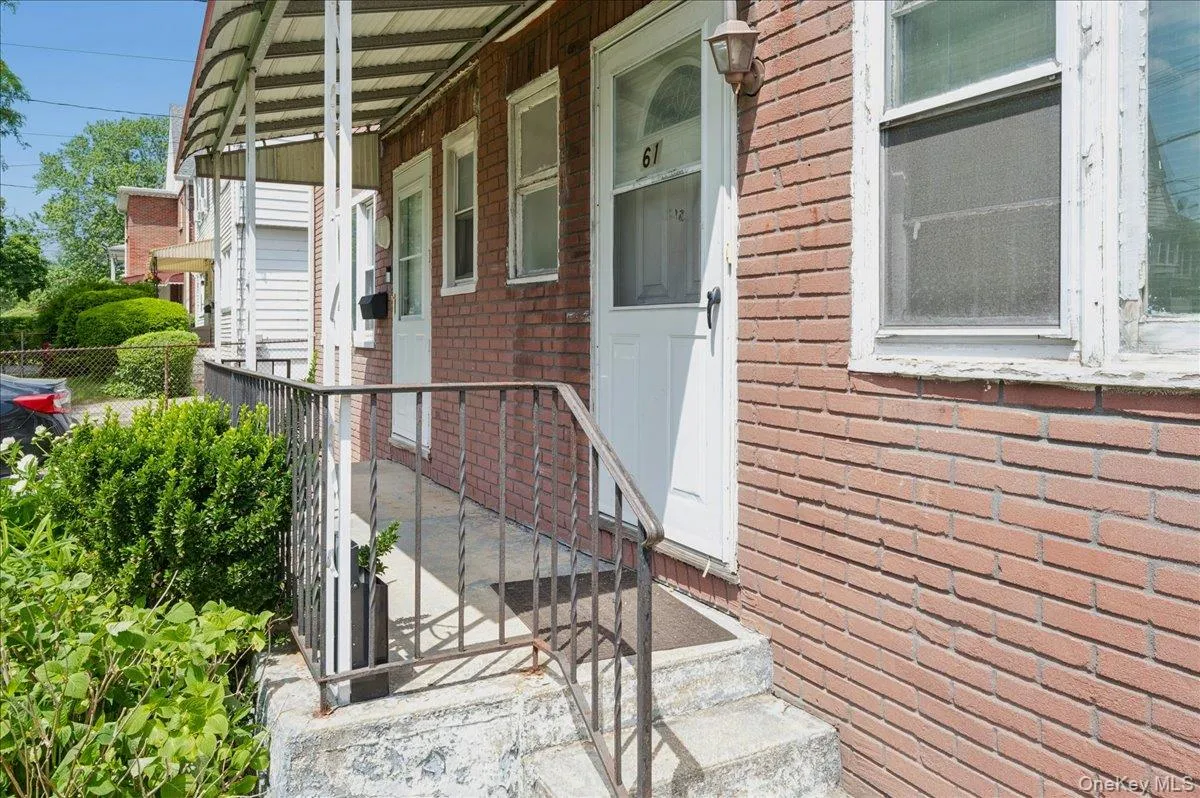 Brick exterior with a covered front porch featuring a metal awning and wrought iron railing Brick exterior with a covered front porch featuring a metal awning and wrought iron railing