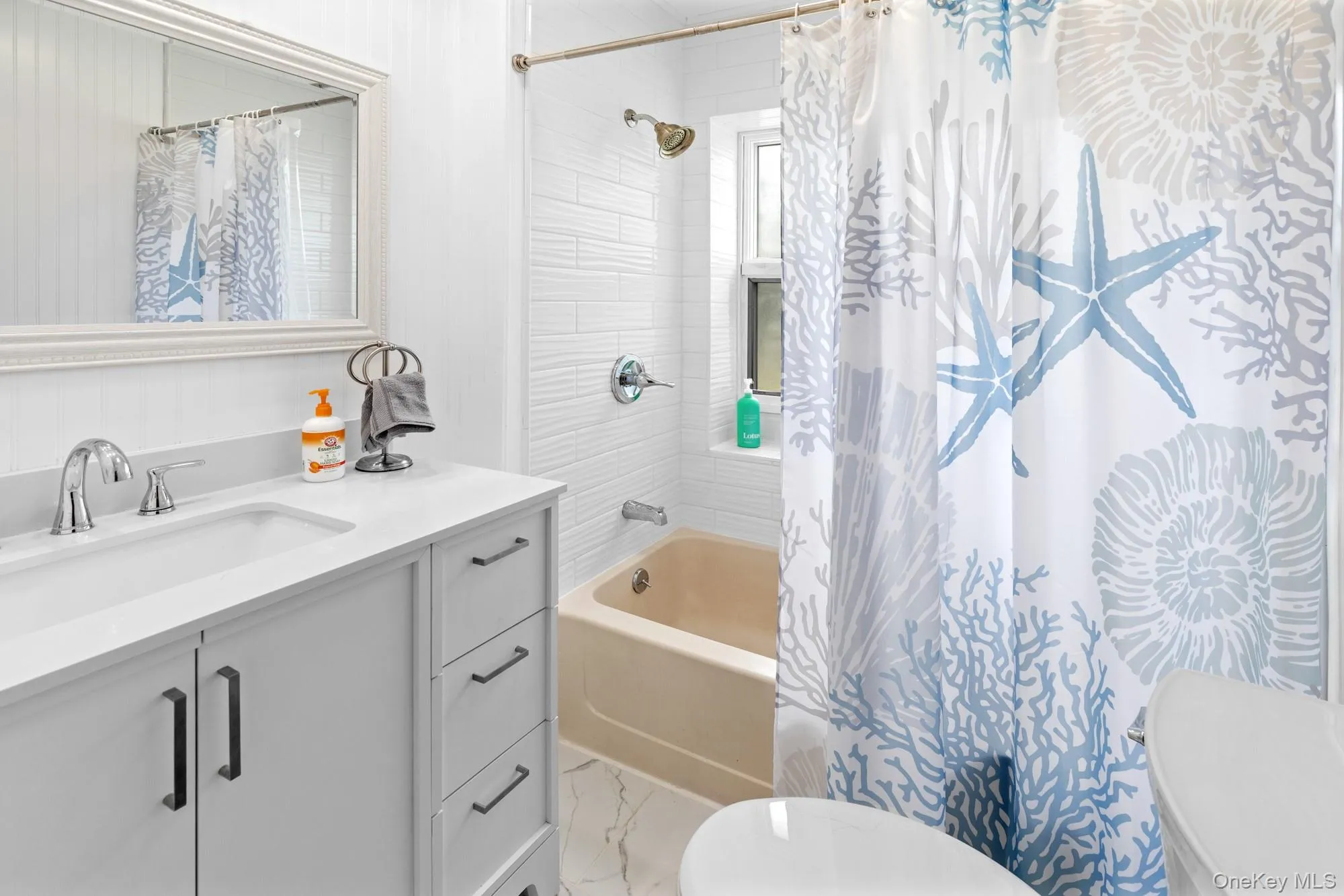 Bathroom with shower / bath combo, vanity, and light marble finish flooring Bathroom with shower / bath combo, vanity, and light marble finish flooring