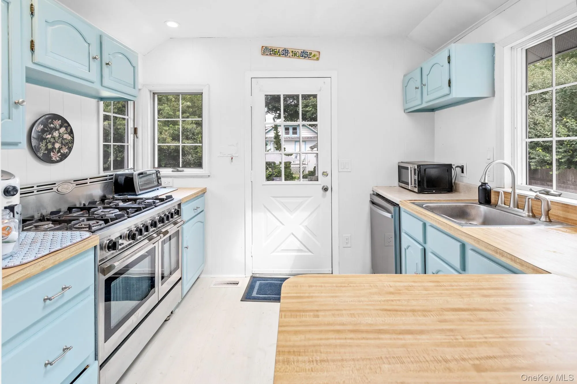 Kitchen with blue cabinets, stainless steel appliances, vaulted ceiling, plenty of natural light, and recessed lighting Kitchen with blue cabinets, stainless steel appliances, vaulted ceiling, plenty of natural light, and recessed lighting
