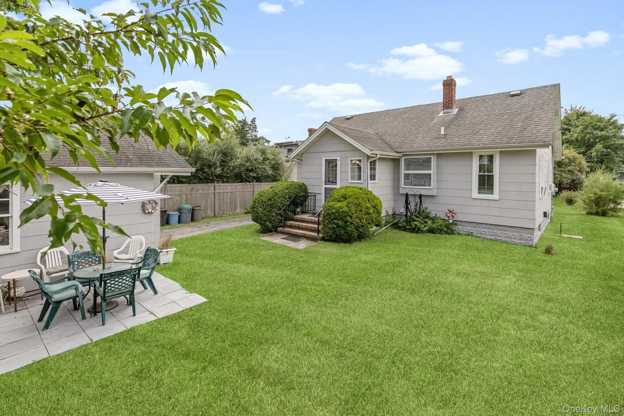 Rear view of property with a chimney, a shingled roof, and a patio area Rear view of property with a chimney, a shingled roof, and a patio area