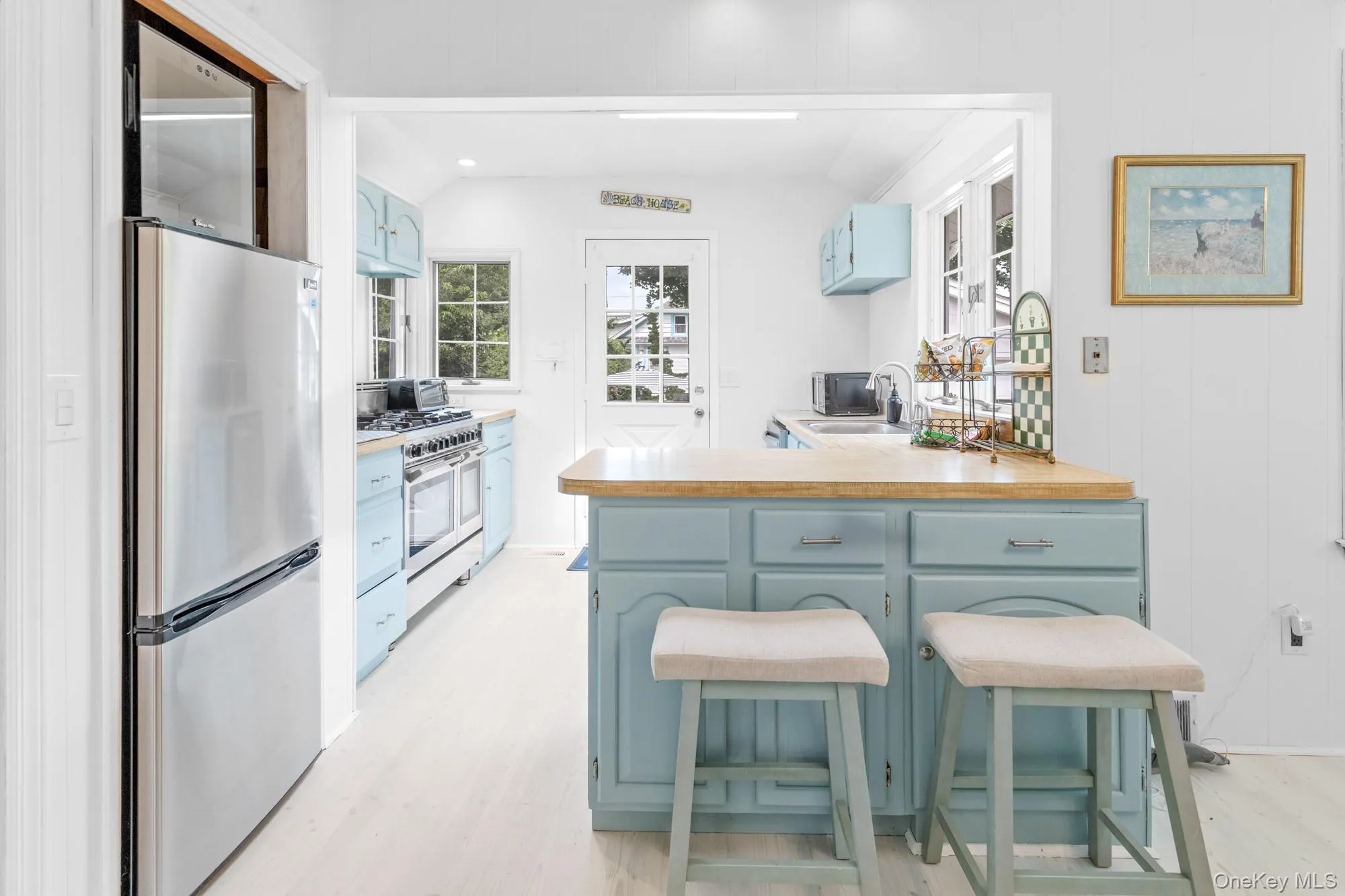 Kitchen with blue cabinetry, a peninsula, a breakfast bar area, stainless steel appliances, and wooden walls Kitchen with blue cabinetry, a peninsula, a breakfast bar area, stainless steel appliances, and wooden walls