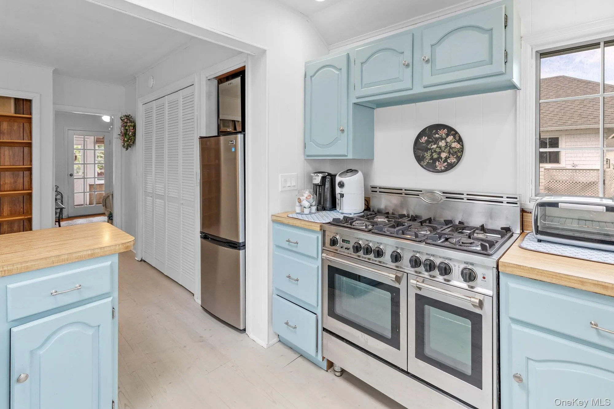 Kitchen with blue cabinets, stainless steel appliances, light countertops, and light wood-type flooring Kitchen with blue cabinets, stainless steel appliances, light countertops, and light wood-type flooring