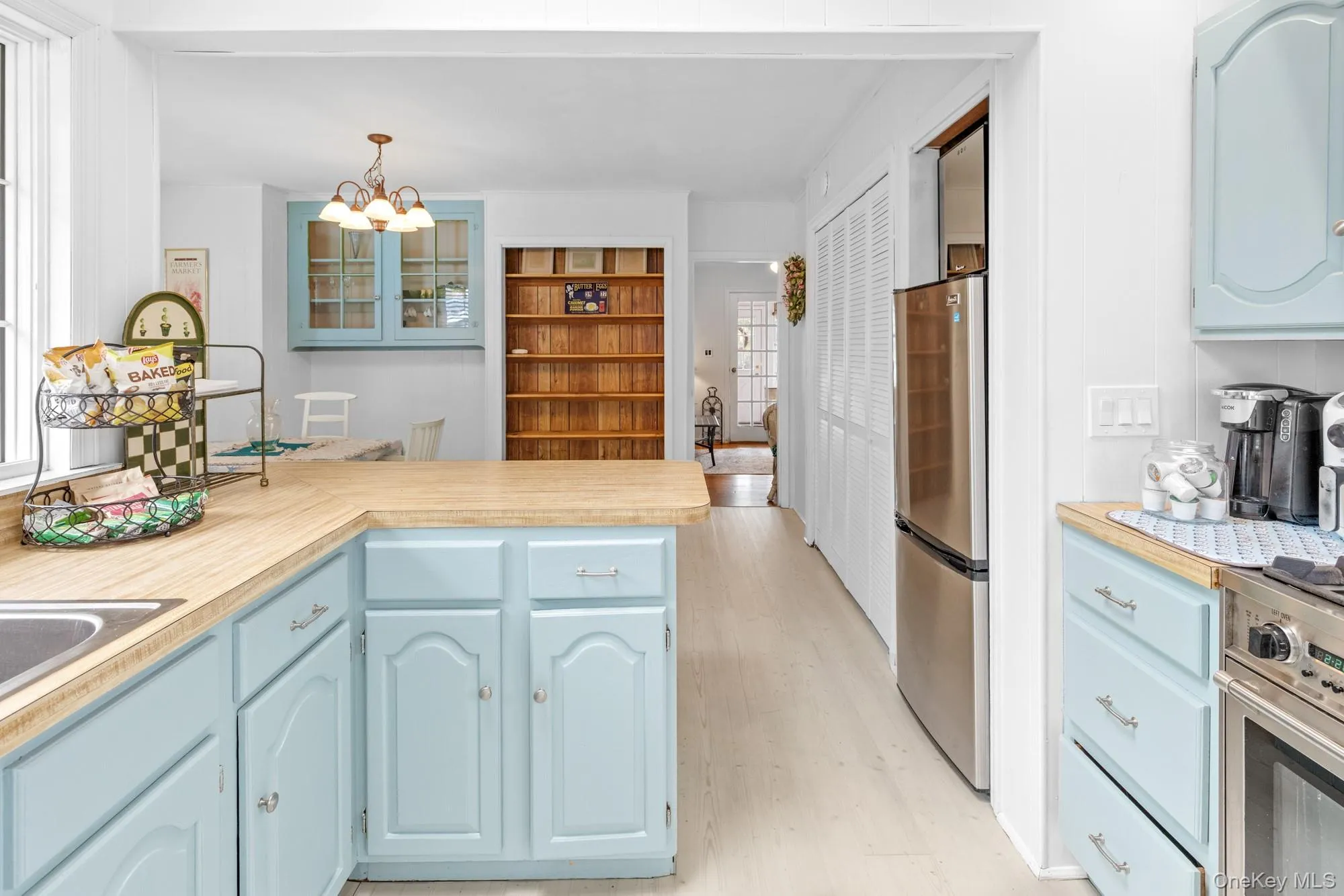 Kitchen with blue cabinetry, stainless steel appliances, a peninsula, light wood finished floors, and pendant lighting Kitchen with blue cabinetry, stainless steel appliances, a peninsula, light wood finished floors, and pendant lighting