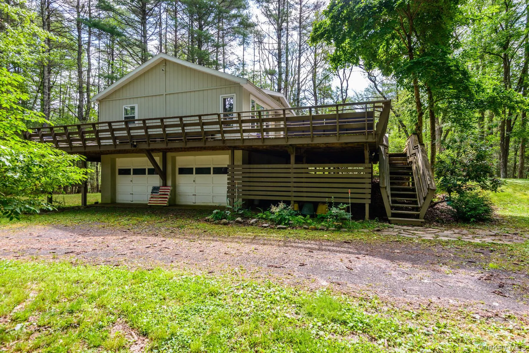 View of front facade with driveway, a garage, a wooden deck, and stairway View of front facade with driveway, a garage, a wooden deck, and stairway