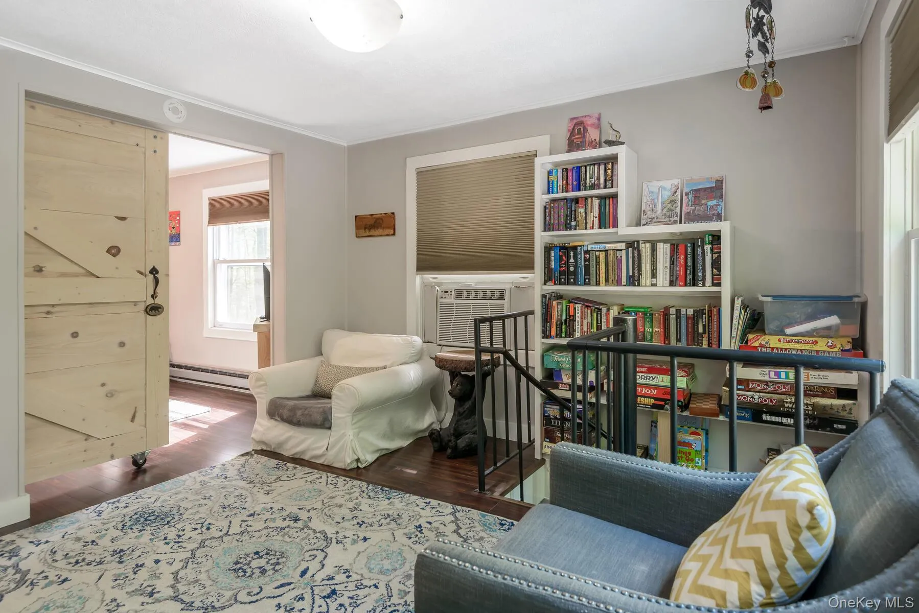 Sitting room featuring baseboard heating, ornamental molding, an upstairs landing, cooling unit, and wood finished floors Sitting room featuring baseboard heating, ornamental molding, an upstairs landing, cooling unit, and wood finished floors