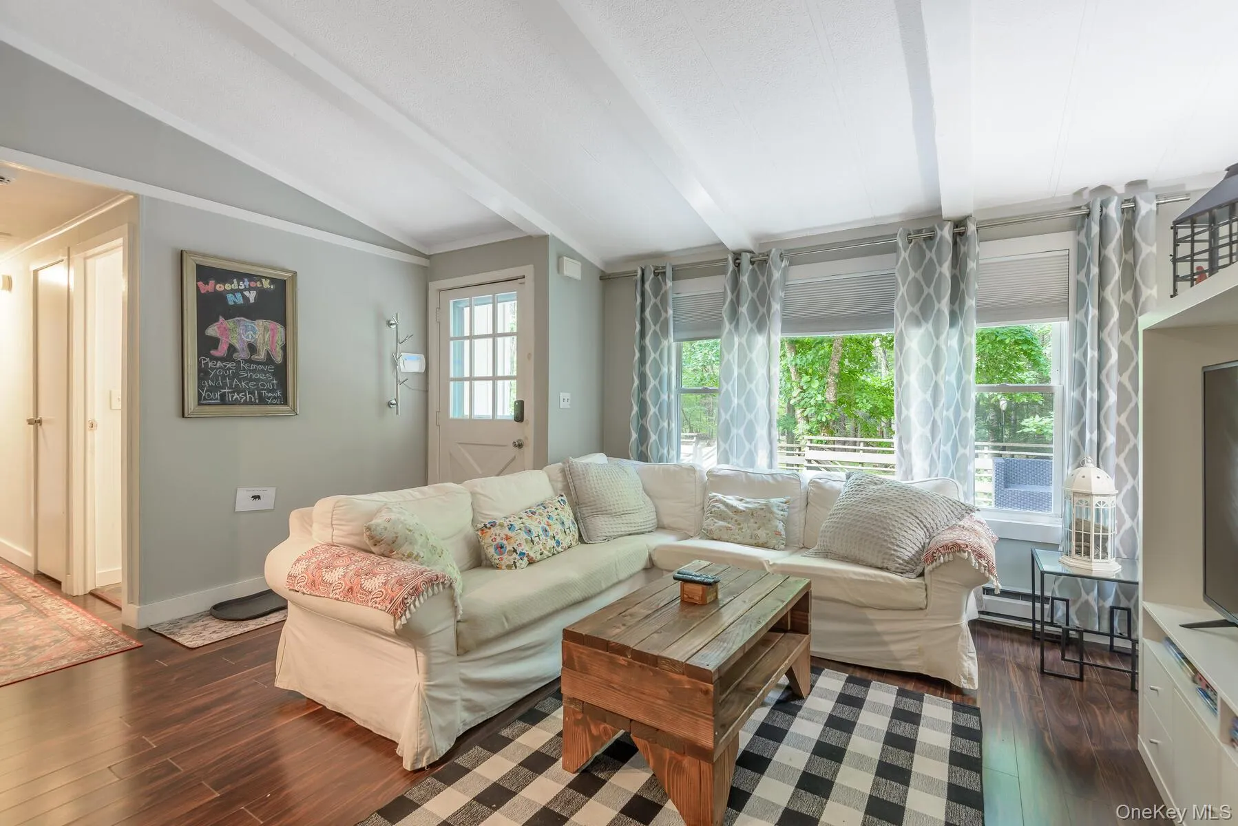 Living area with lofted ceiling with beams, dark wood finished floors, and baseboards Living area with lofted ceiling with beams, dark wood finished floors, and baseboards