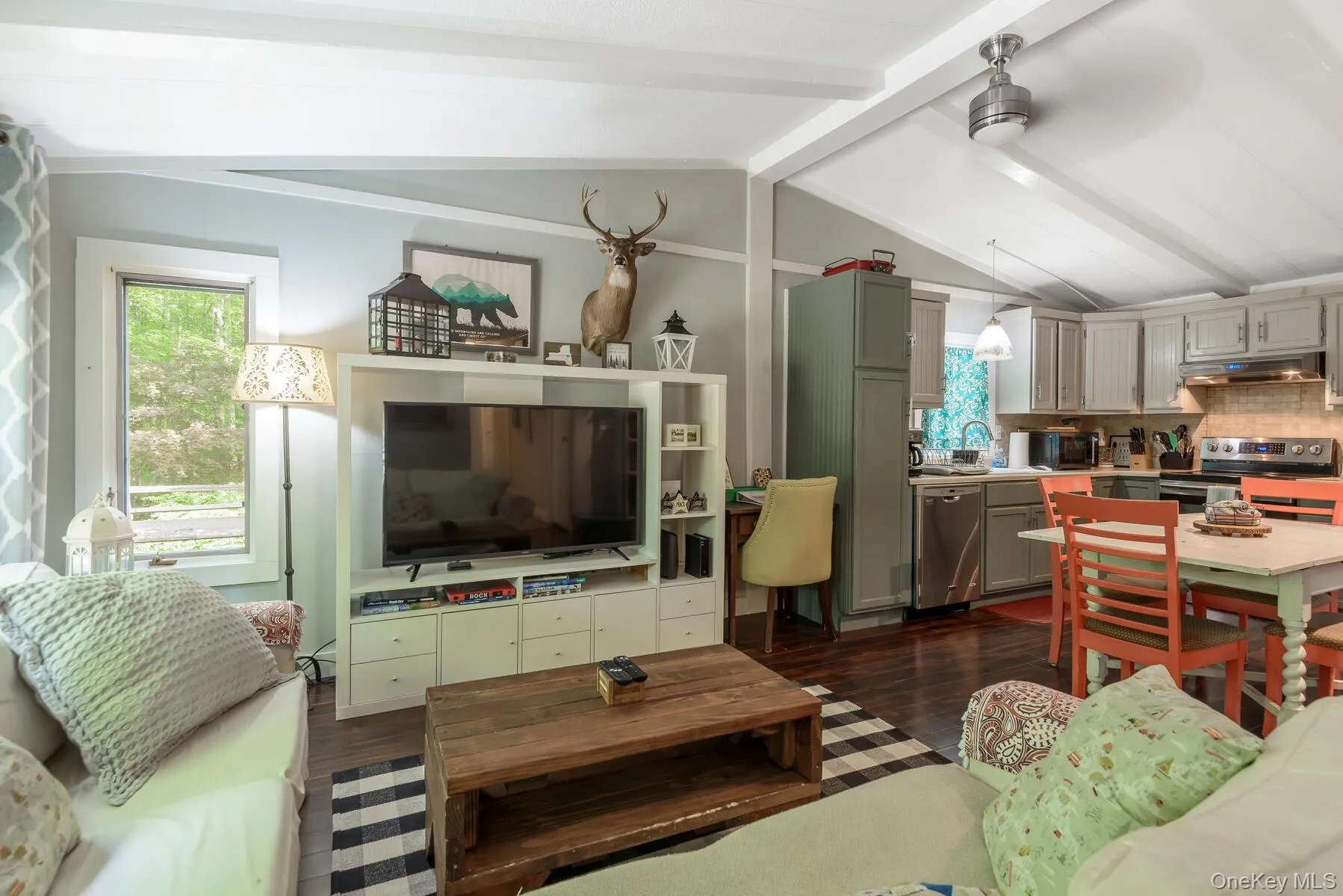Living area with dark wood-style floors, vaulted ceiling with beams, and a healthy amount of sunlight Living area with dark wood-style floors, vaulted ceiling with beams, and a healthy amount of sunlight
