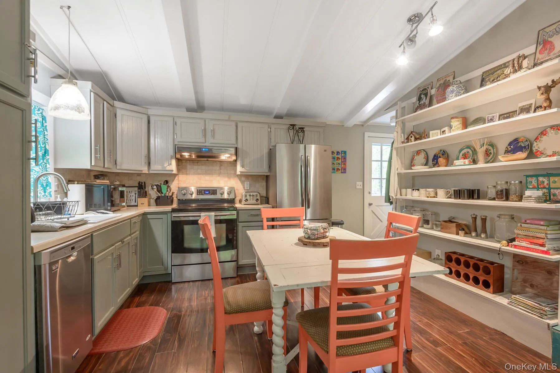Kitchen with ventilation hood, appliances with stainless steel finishes, light countertops, decorative backsplash, and dark wood-style floors Kitchen with ventilation hood, appliances with stainless steel finishes, light countertops, decorative backsplash, and dark wood-style floors