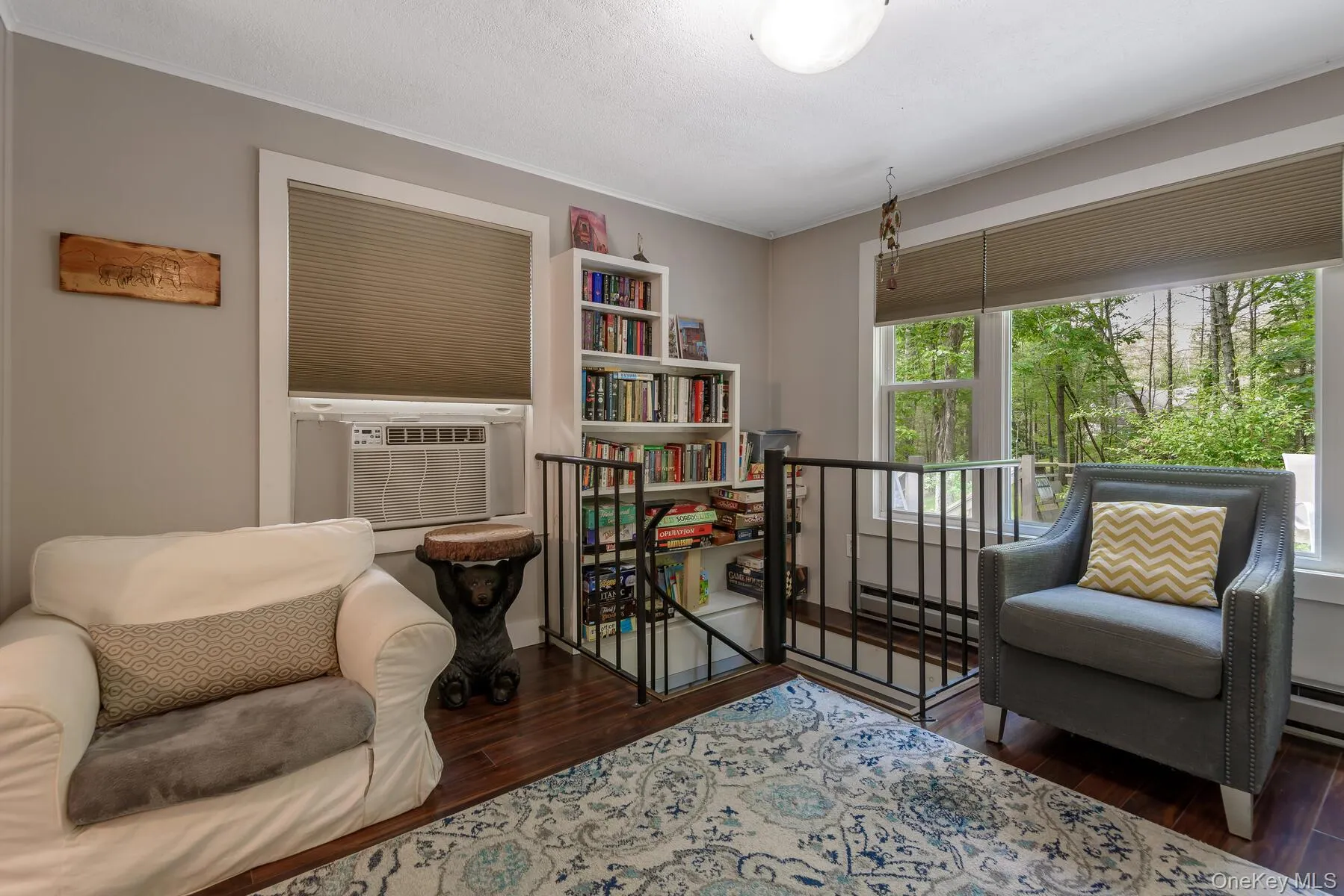 Living area with ornamental molding, an upstairs landing, cooling unit, a baseboard radiator, and wood finished floors Living area with ornamental molding, an upstairs landing, cooling unit, a baseboard radiator, and wood finished floors