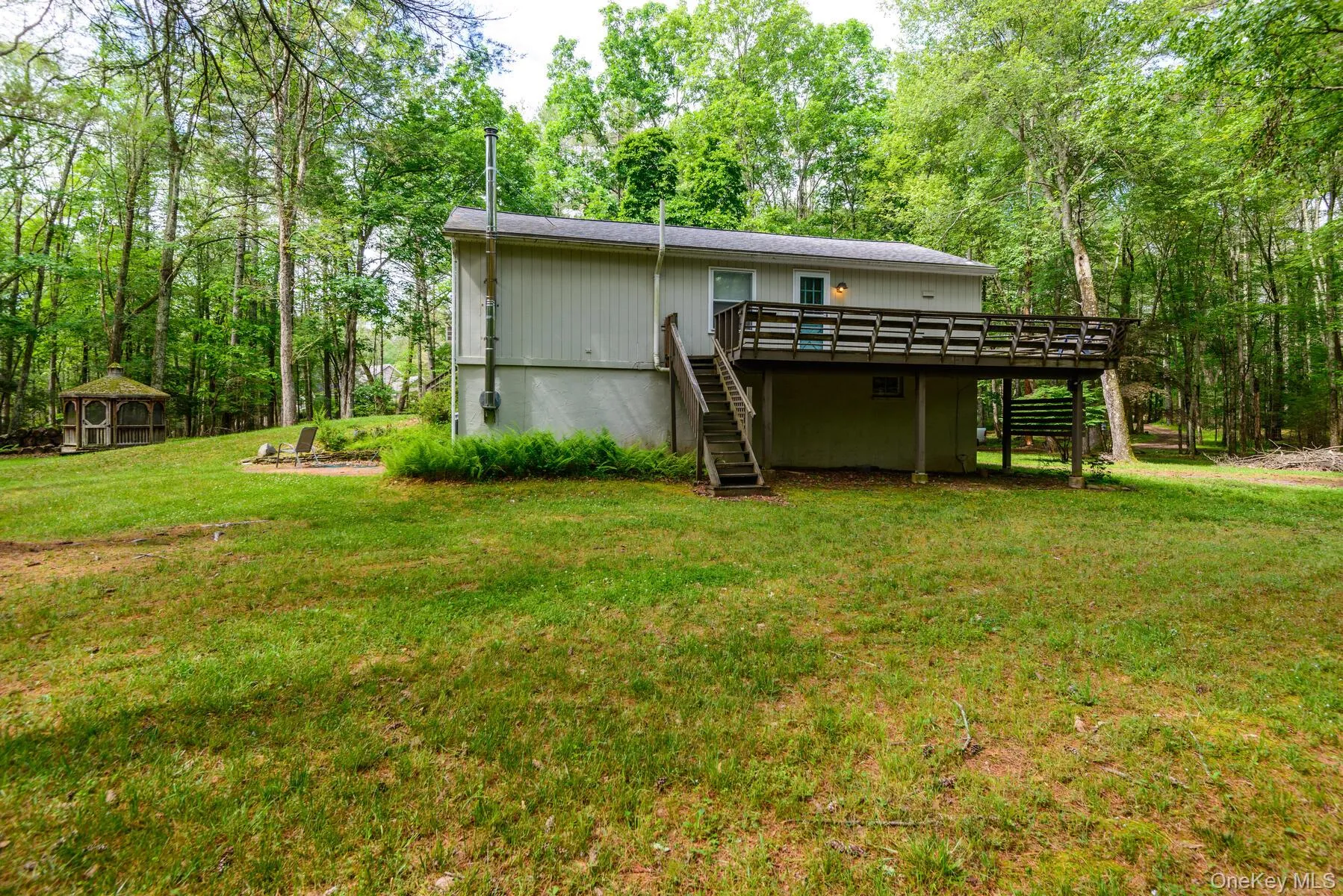 Back of property with a yard, stairway, and a wooden deck Back of property with a yard, stairway, and a wooden deck