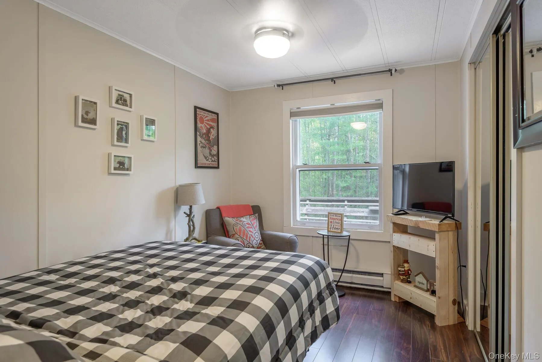 Bedroom featuring dark wood-style flooring, a baseboard heating unit, and crown molding Bedroom featuring dark wood-style flooring, a baseboard heating unit, and crown molding