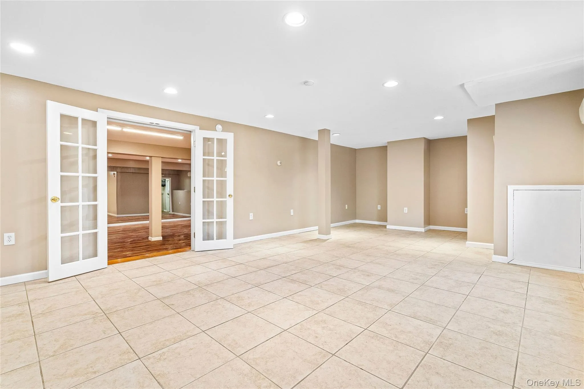 Empty room featuring french doors, baseboards, and light tile patterned floors Empty room featuring french doors, baseboards, and light tile patterned floors