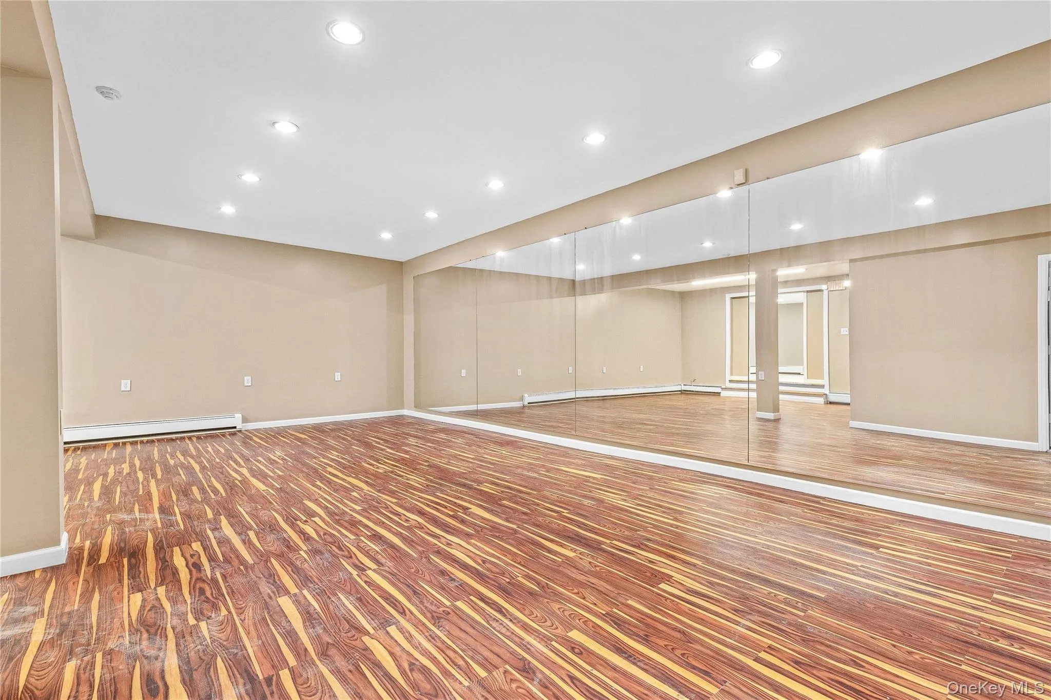 Below grade area with baseboard heating, a baseboard heating unit, light wood finished floors, baseboards, and recessed lighting Below grade area with baseboard heating, a baseboard heating unit, light wood finished floors, baseboards, and recessed lighting