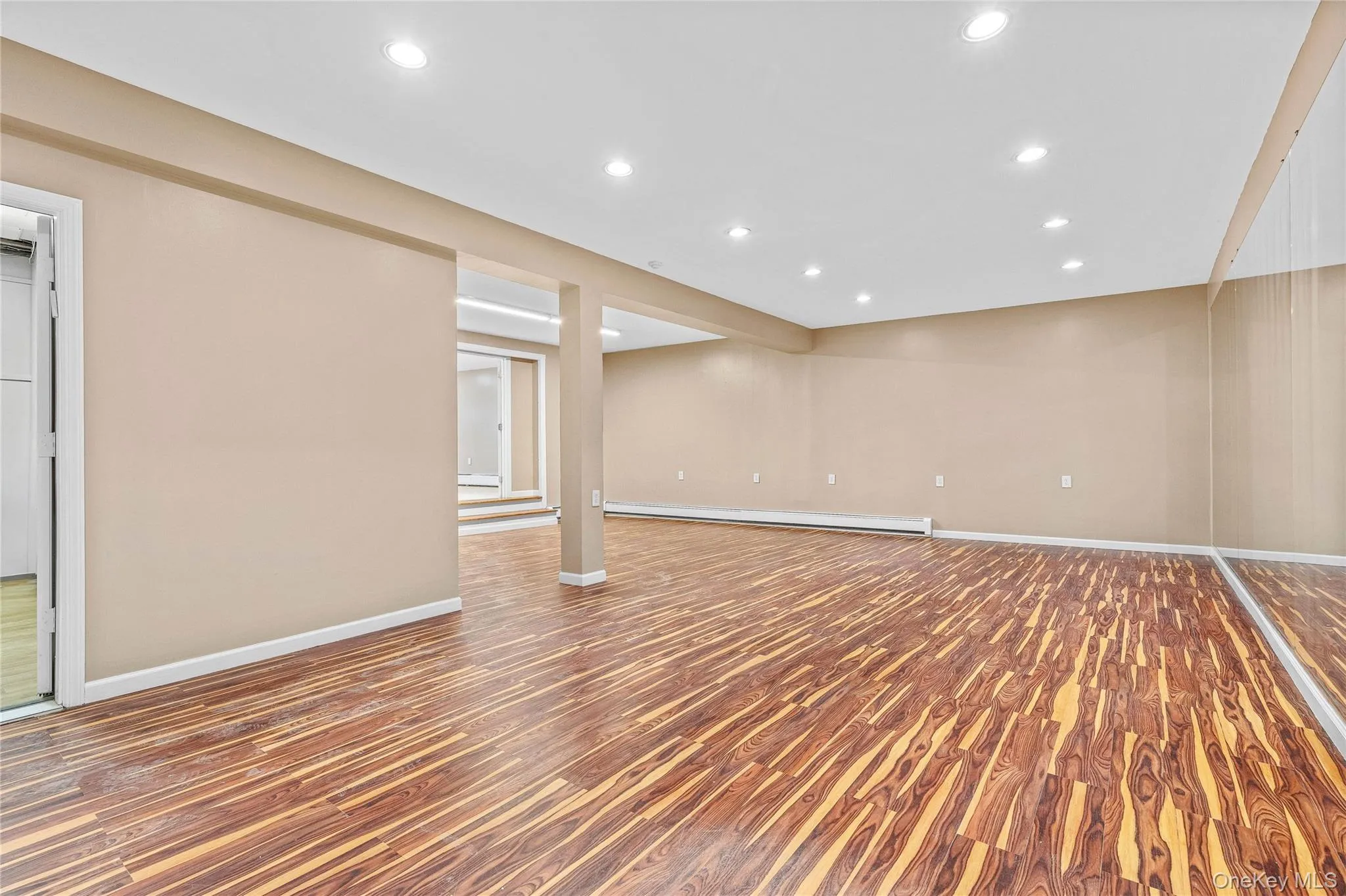 Below grade area featuring baseboards, wood finished floors, recessed lighting, and a baseboard radiator Below grade area featuring baseboards, wood finished floors, recessed lighting, and a baseboard radiator