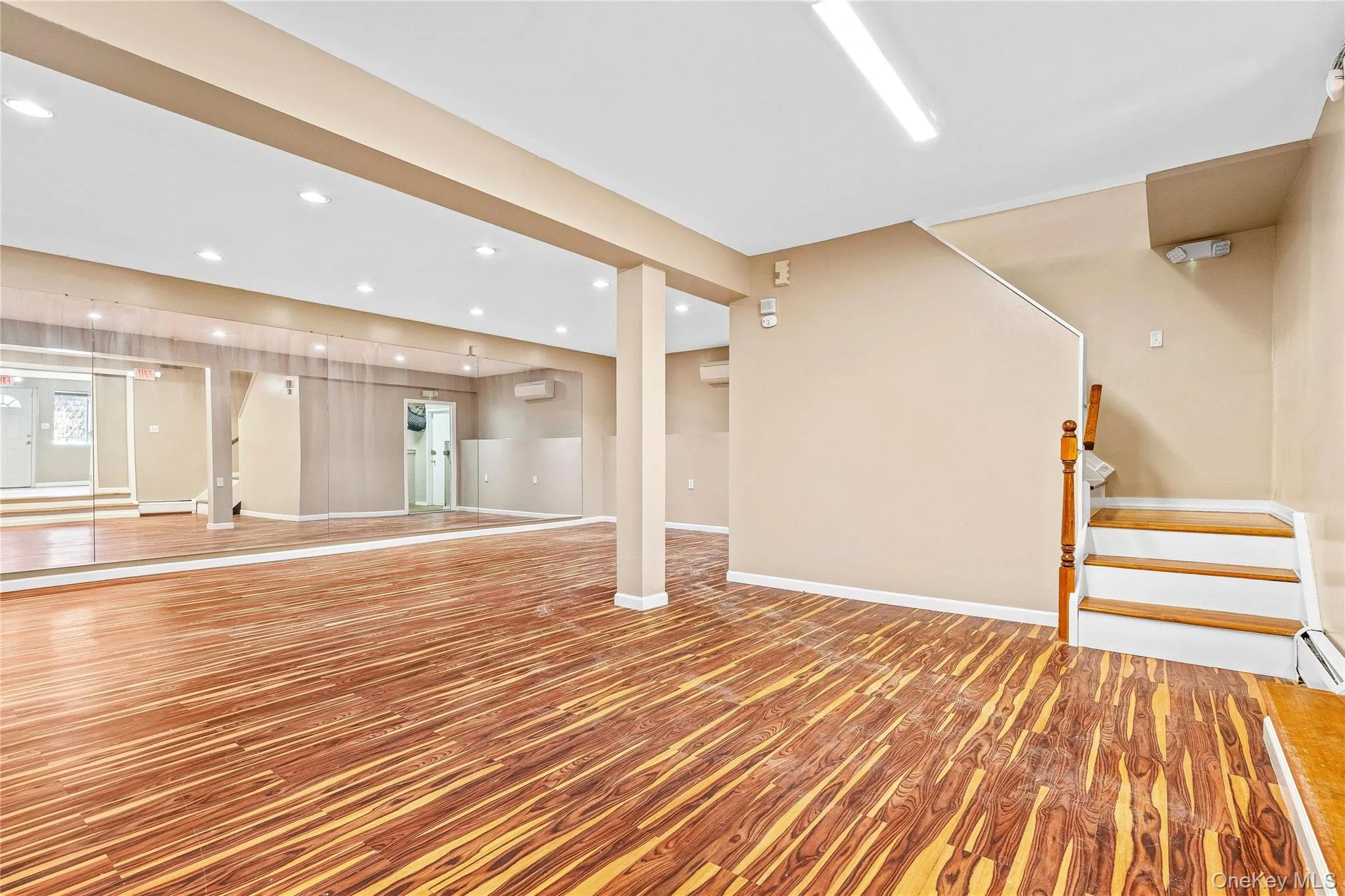 Exercise room with baseboards, a wall unit AC, wood finished floors, and recessed lighting Exercise room with baseboards, a wall unit AC, wood finished floors, and recessed lighting