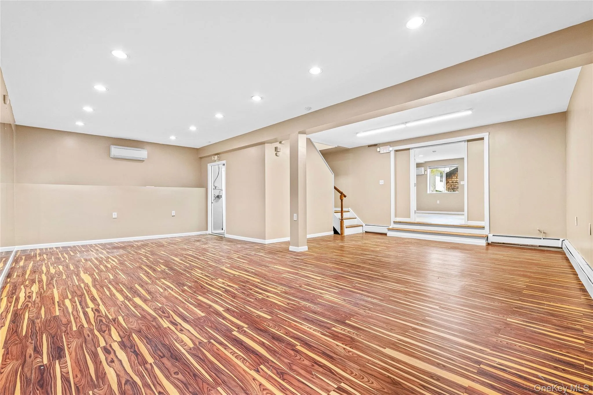 Basement with wood finished floors, stairs, a wall mounted AC, and recessed lighting Basement with wood finished floors, stairs, a wall mounted AC, and recessed lighting